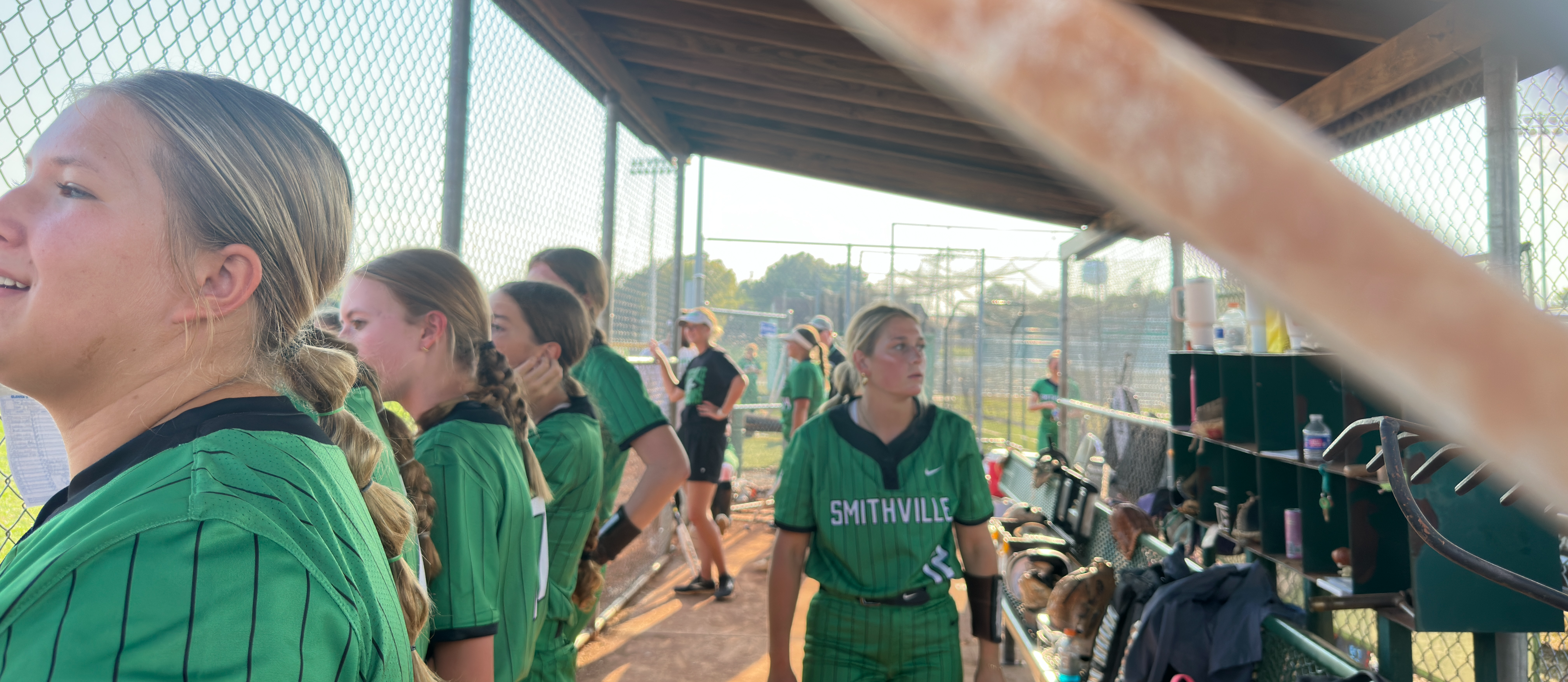 softball girls cheering for their teammate from the dugout