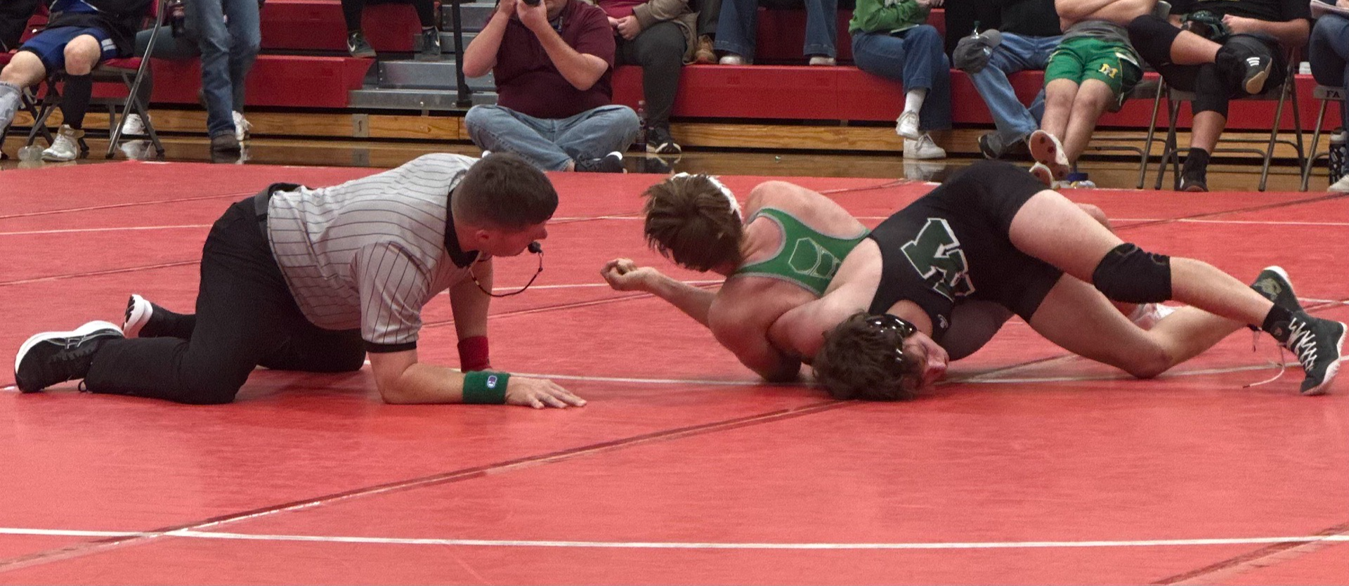 A referee gets down to see the wrestlers on the mat and watch for a pin