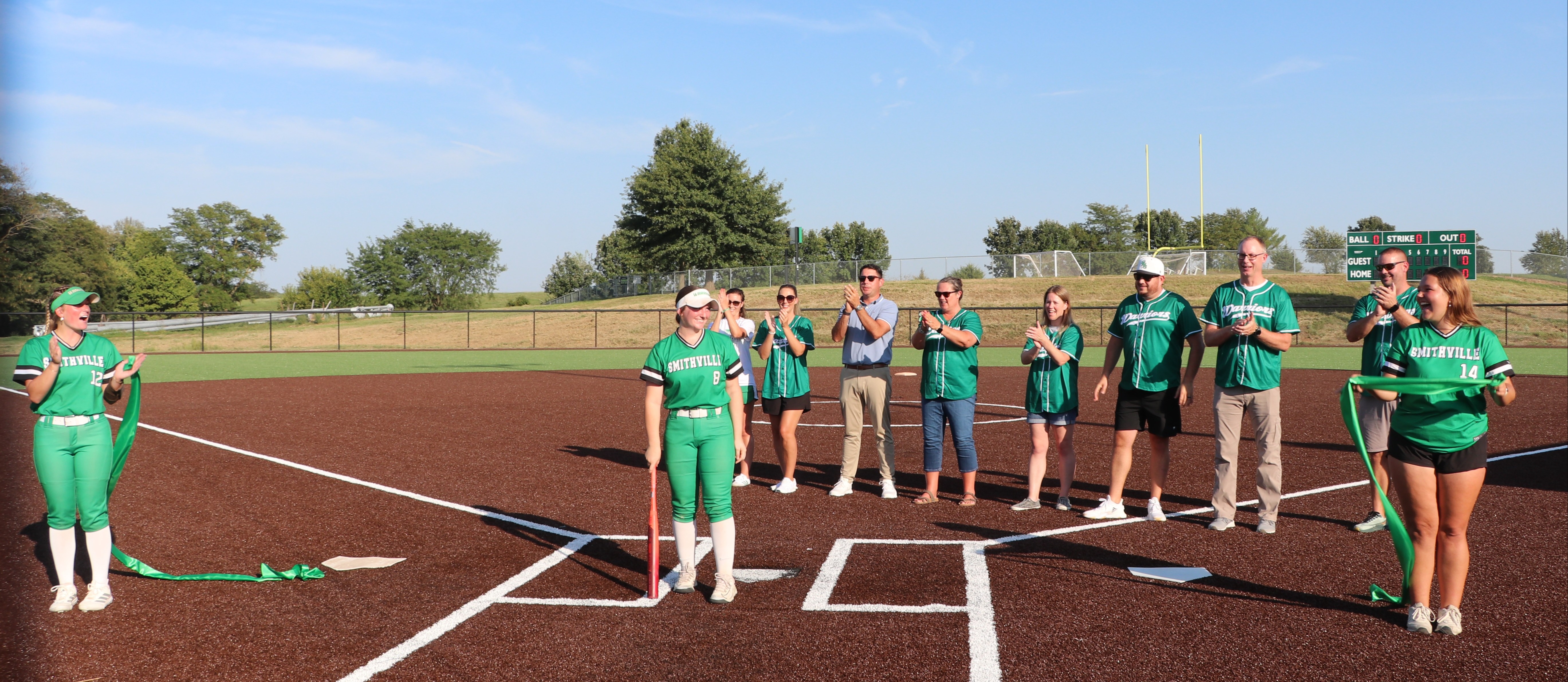 The softball team poses with board members for the first pitch ceremony