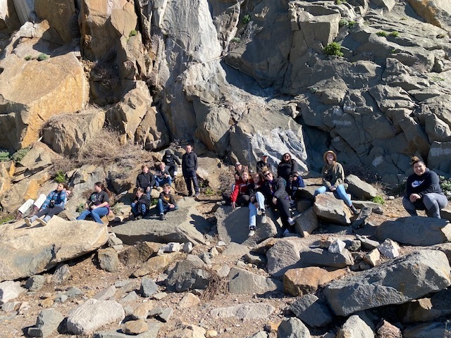 students stand in front of giant rock formation