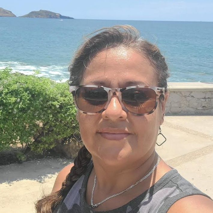 headshot of Betty standing in front of the ocean