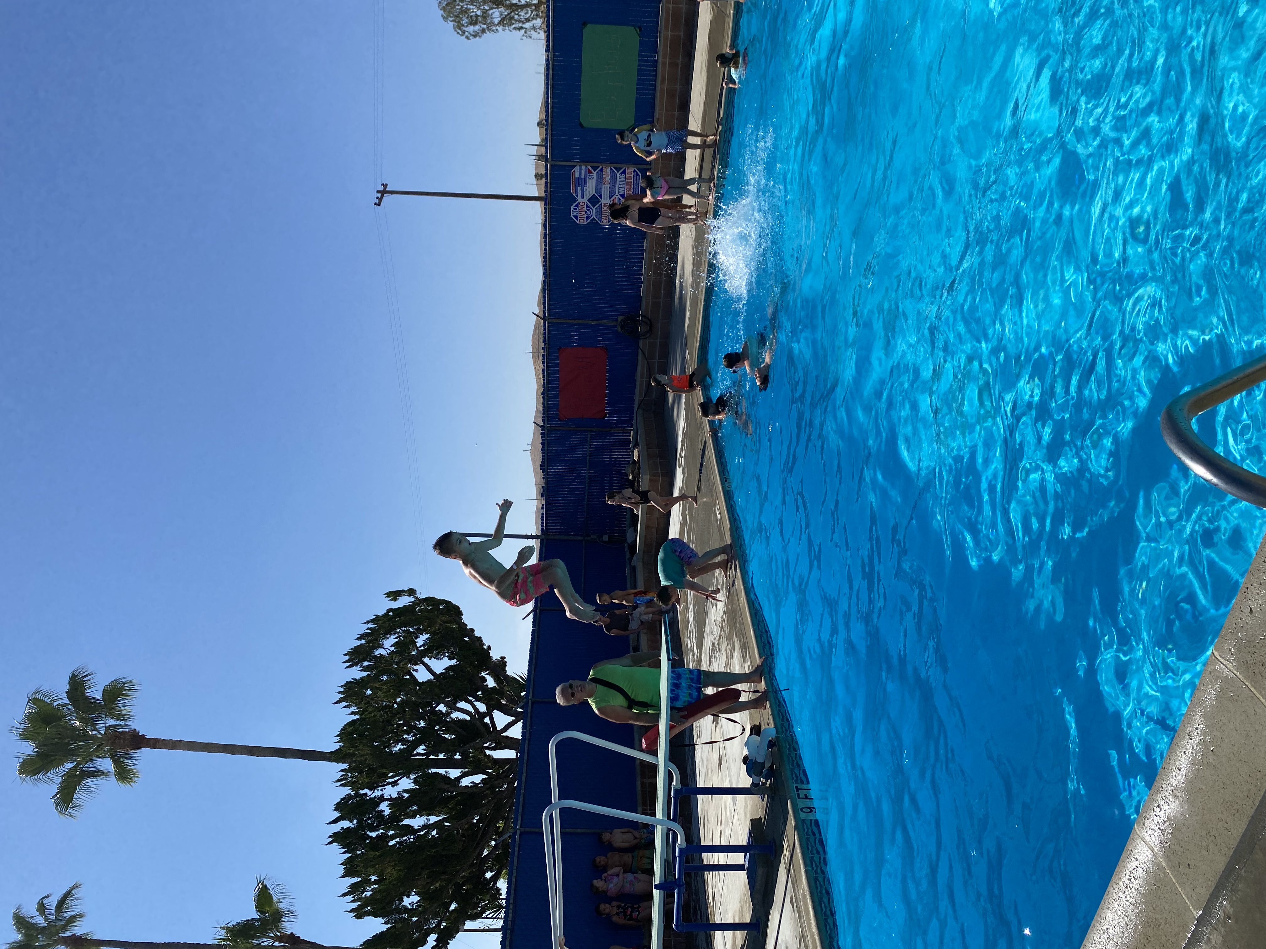 Student jumping off diving board into pool