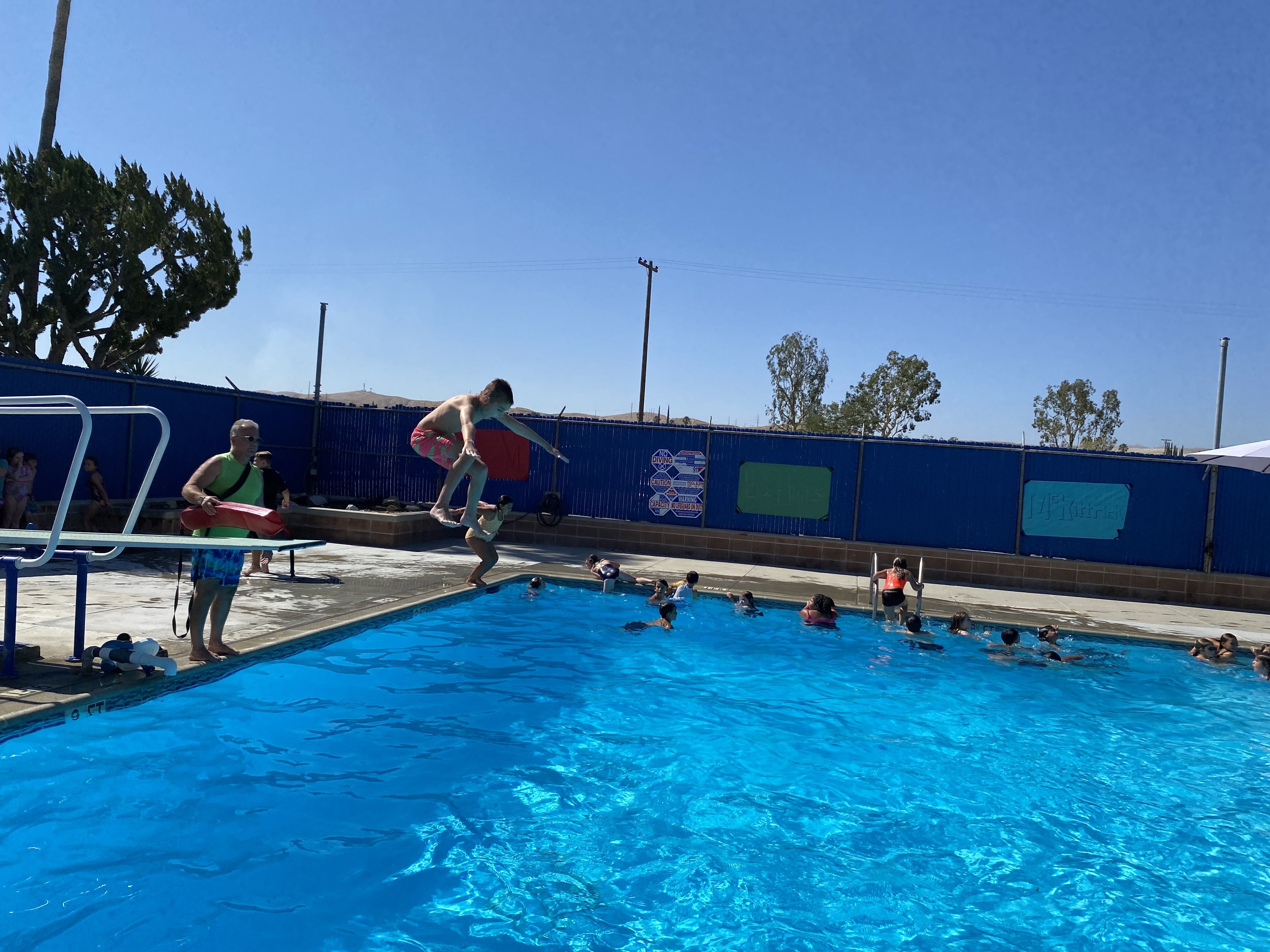 Student jumping off diving board into pool