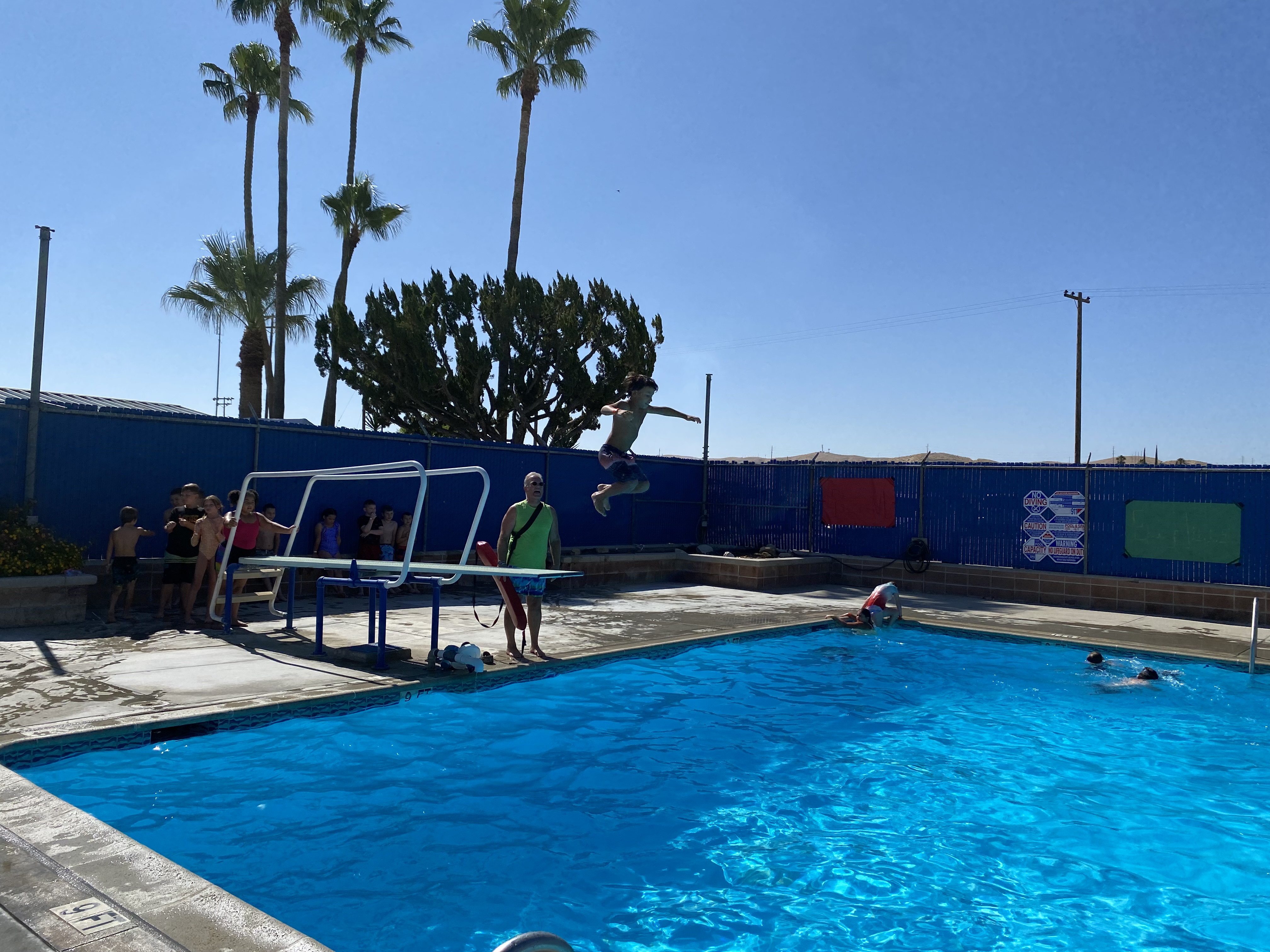 Student jumping off diving board into pool