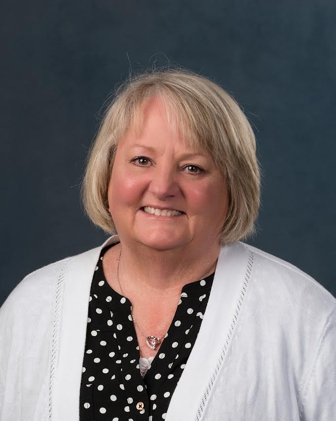 Linda Vernon headshot: woman wearing black shirt with white polka dots and a white cardigan