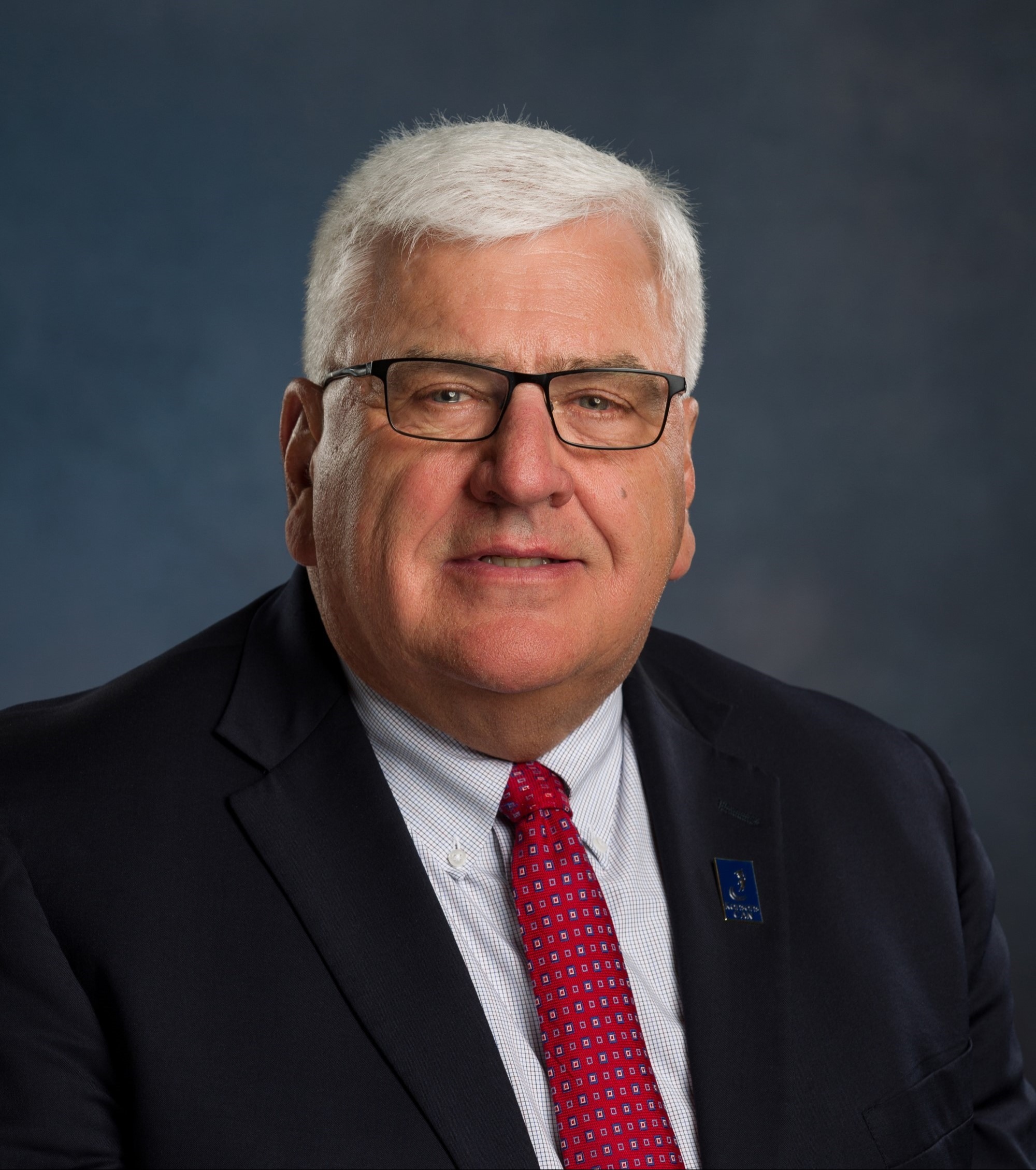 Loren Feldkamp headshot: white shirt, red tie, black suit coat