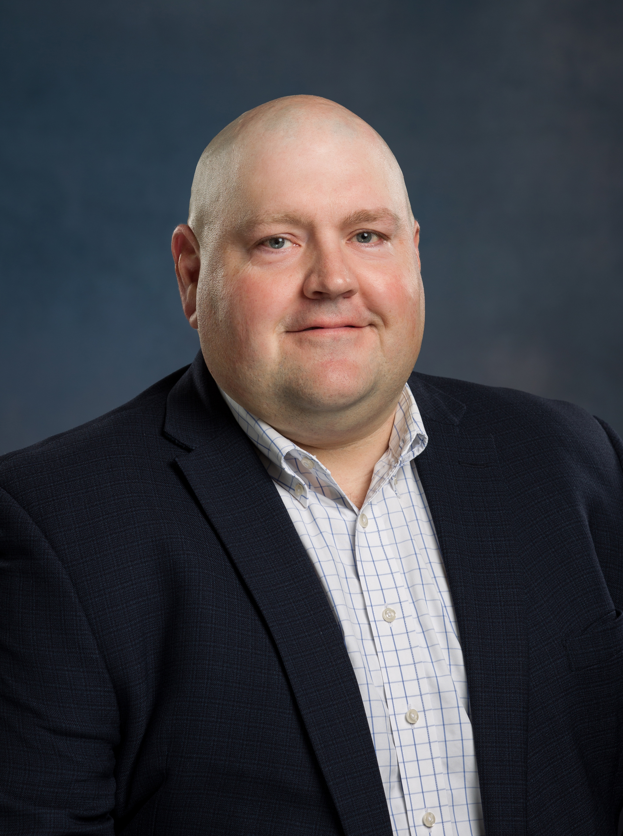 Justin Sturgeon headshot wearing white button up shirt and black suit coat