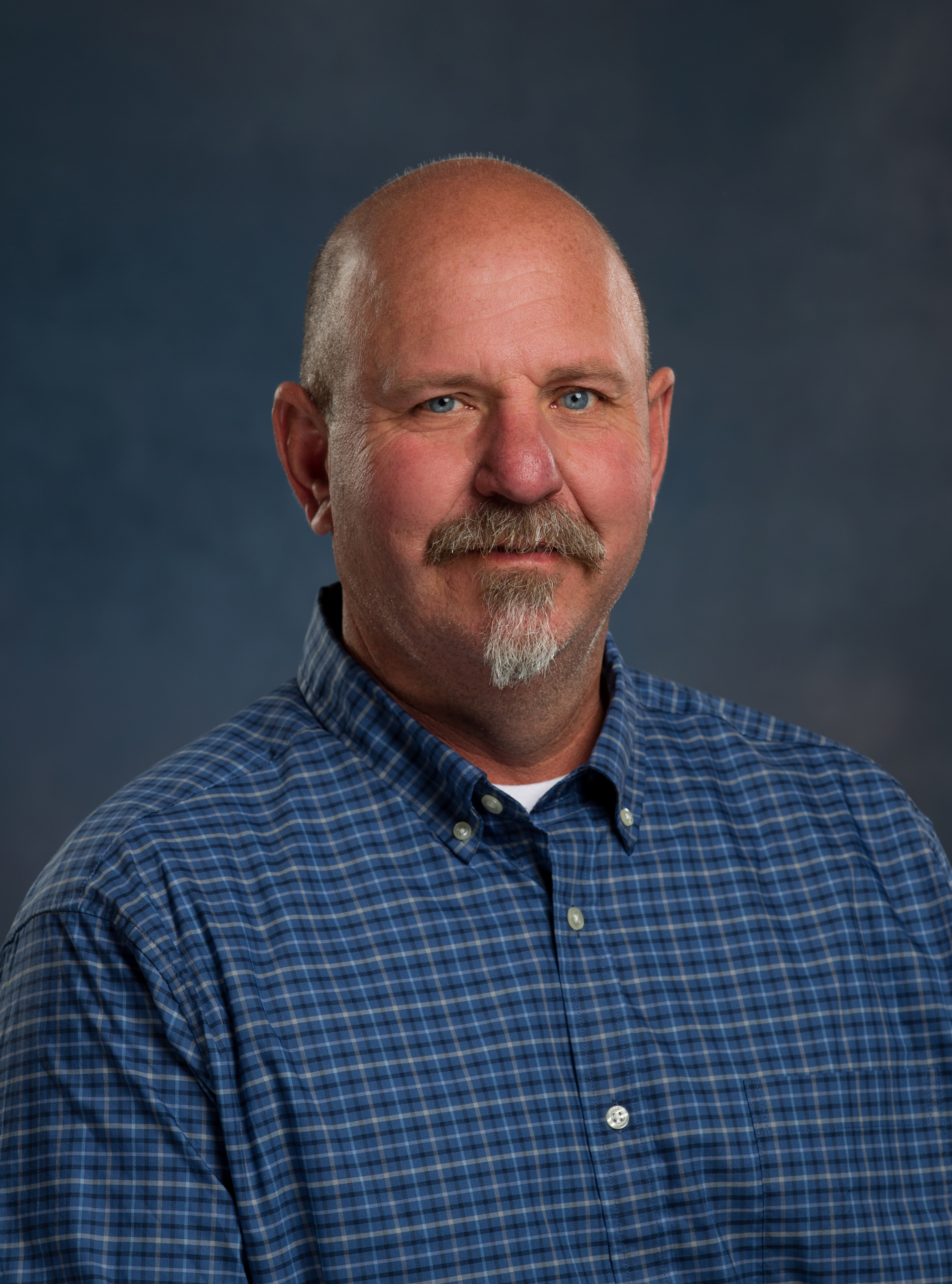 Chris Gratton headshot wearing blue plaid button up shirt