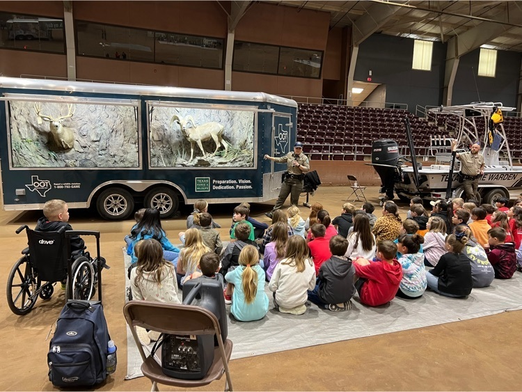 elementary students sit in front of an agriculture vehicle for a presentation