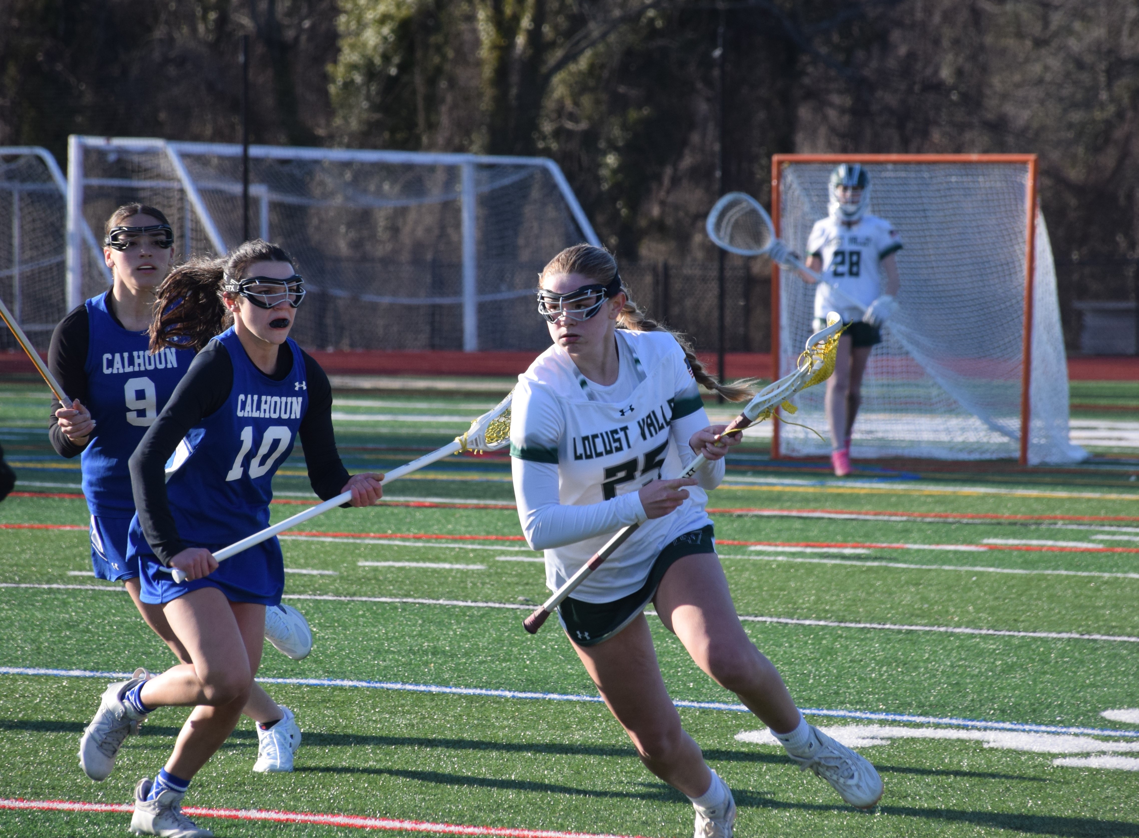 A Locust Valley High School varsity lacrosse player carries the ball up field.