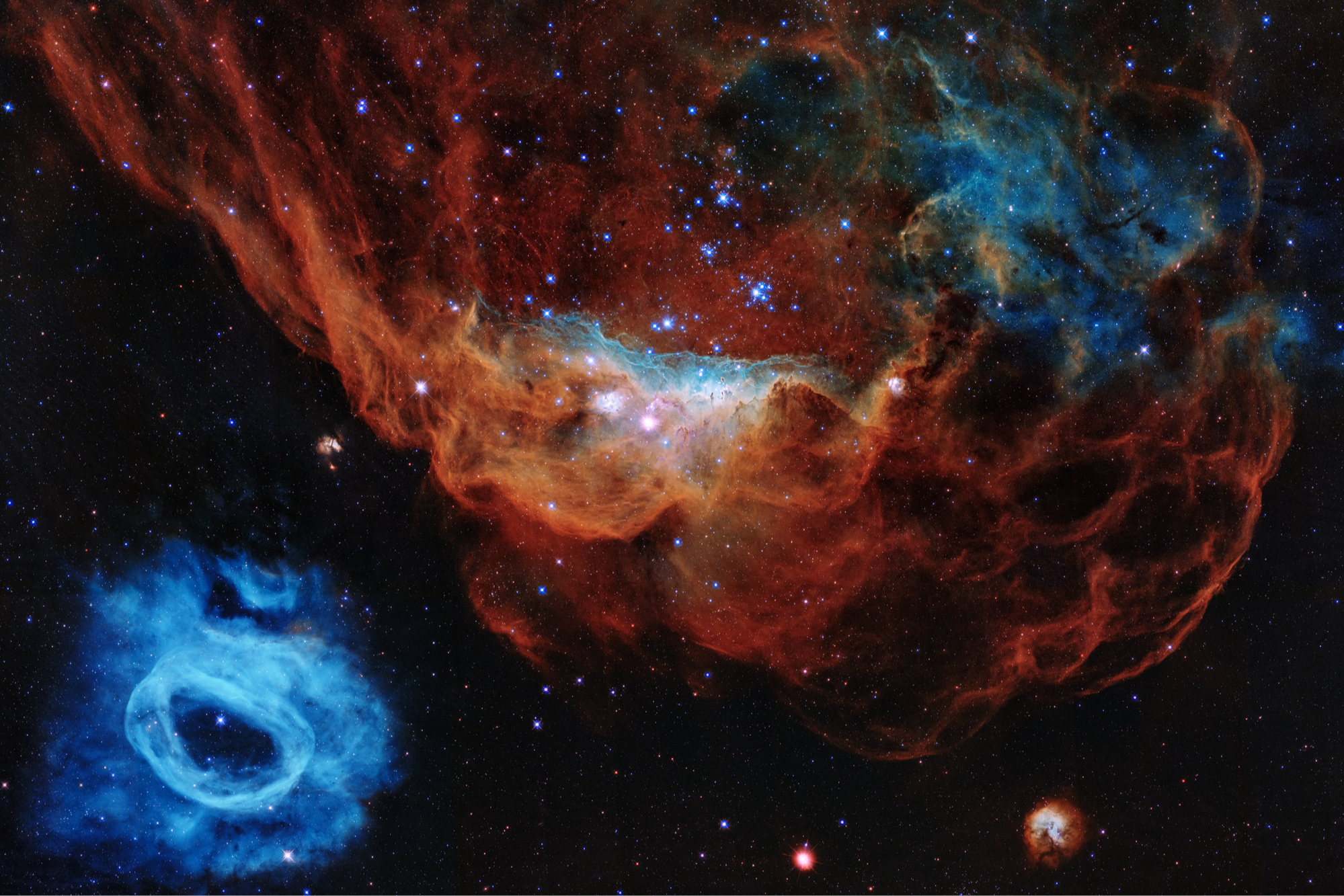 A nebula with vibrant red and blue colors, featuring a large, irregular shape and a smaller blue object in the foreground.