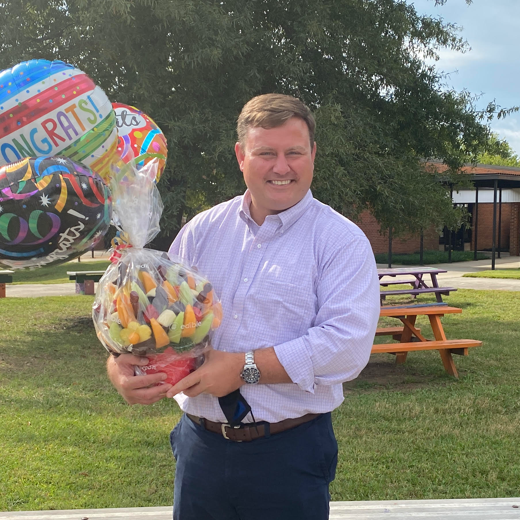 Curry Bryan, ABSS Principal of the Year holding balloons and gift basket 