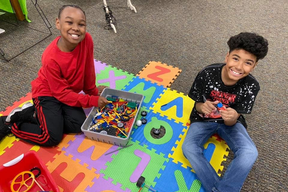 students on a alphabet carpet in classroom working with legos