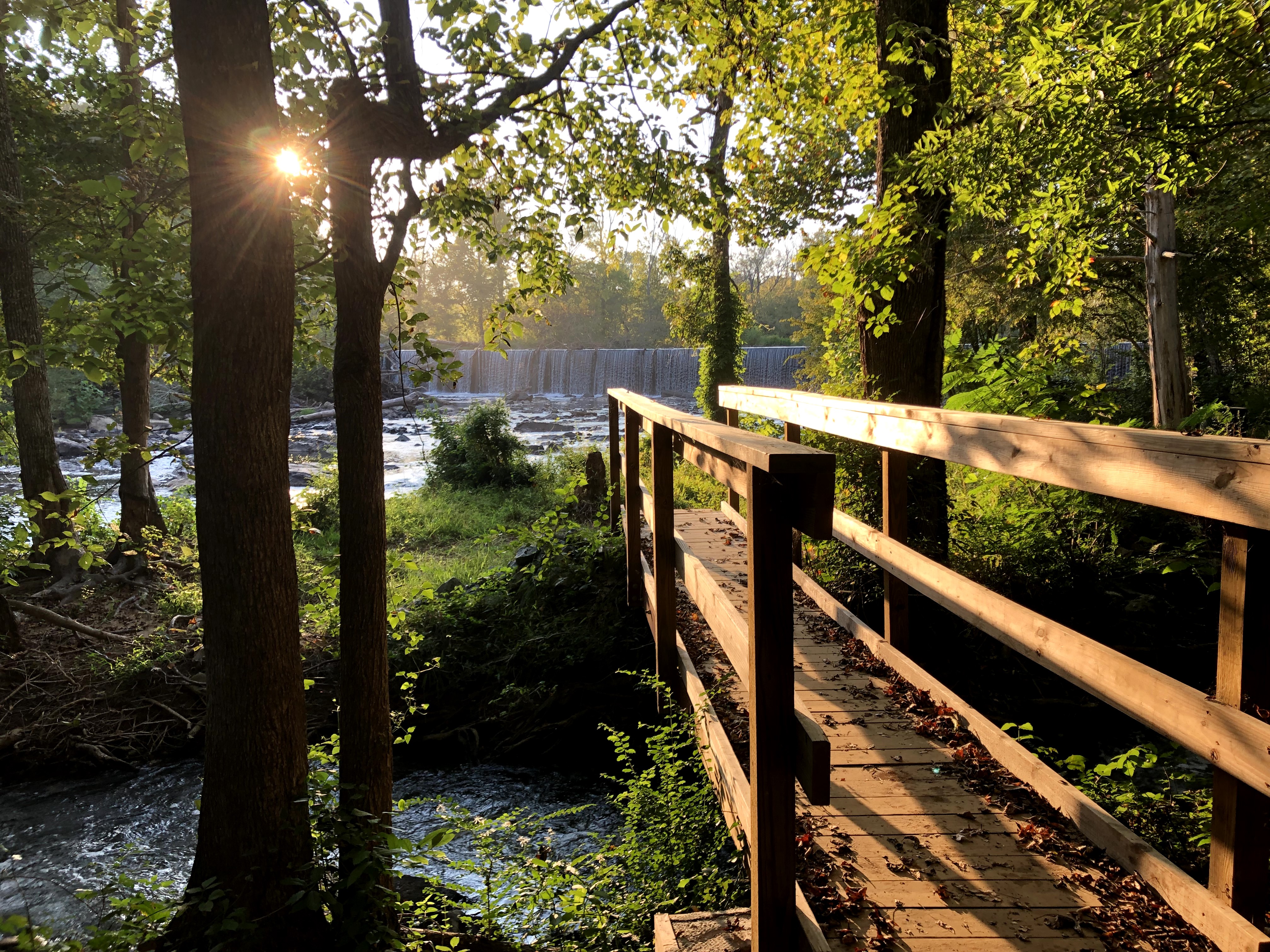Photograph of a bridge along the Glencoe Haw River trail facing the dam and river