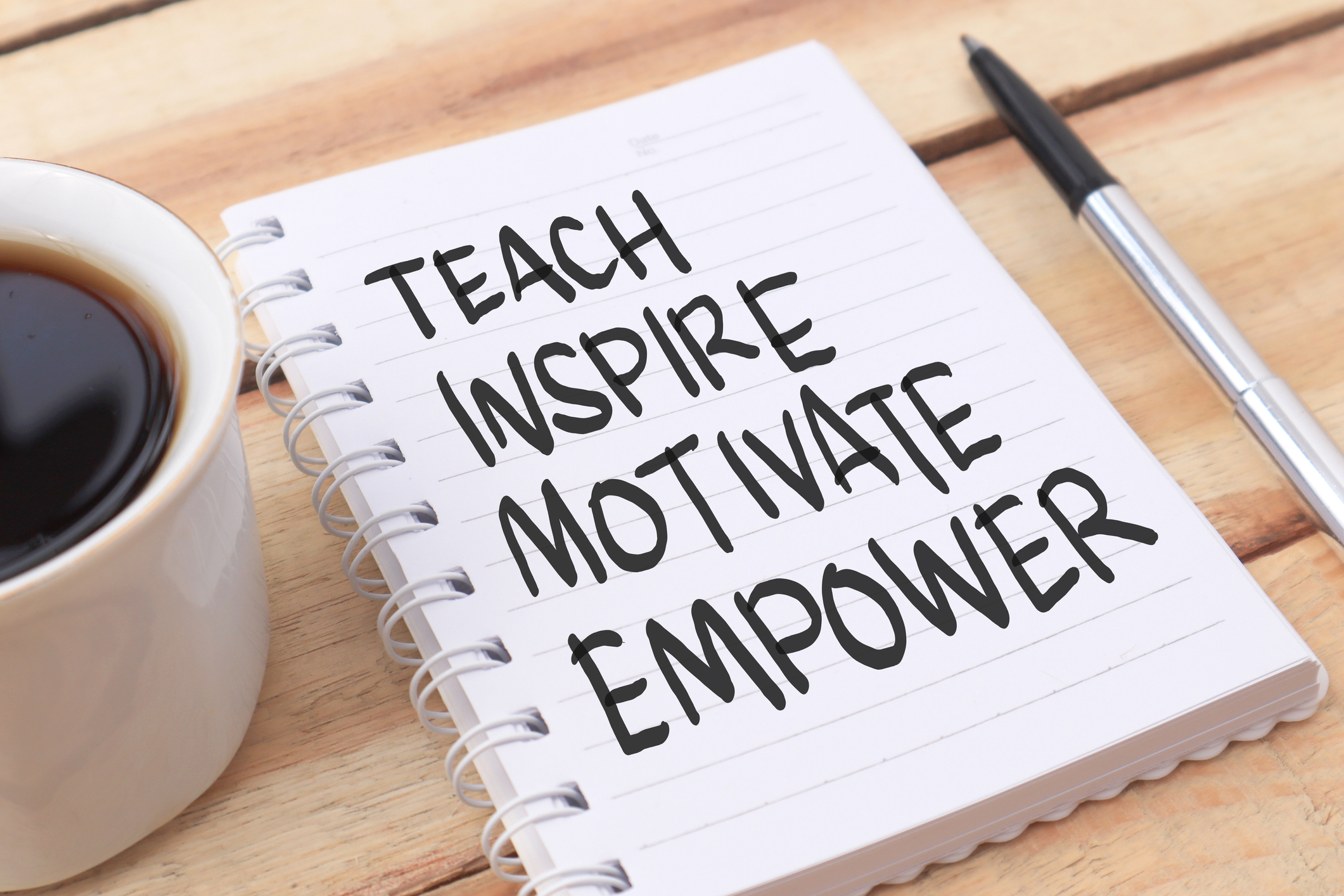 Photograph of a notebook with the text Teach Inspire Motivate Empower