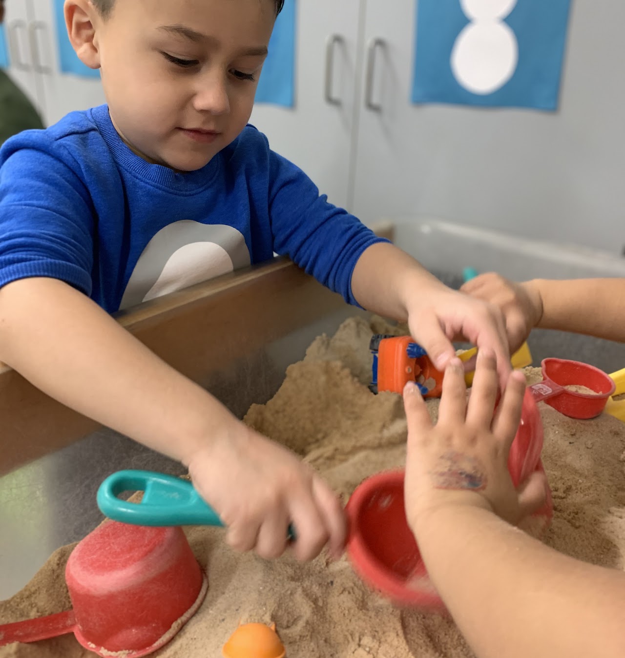 Pre-K students playing in a sandbox