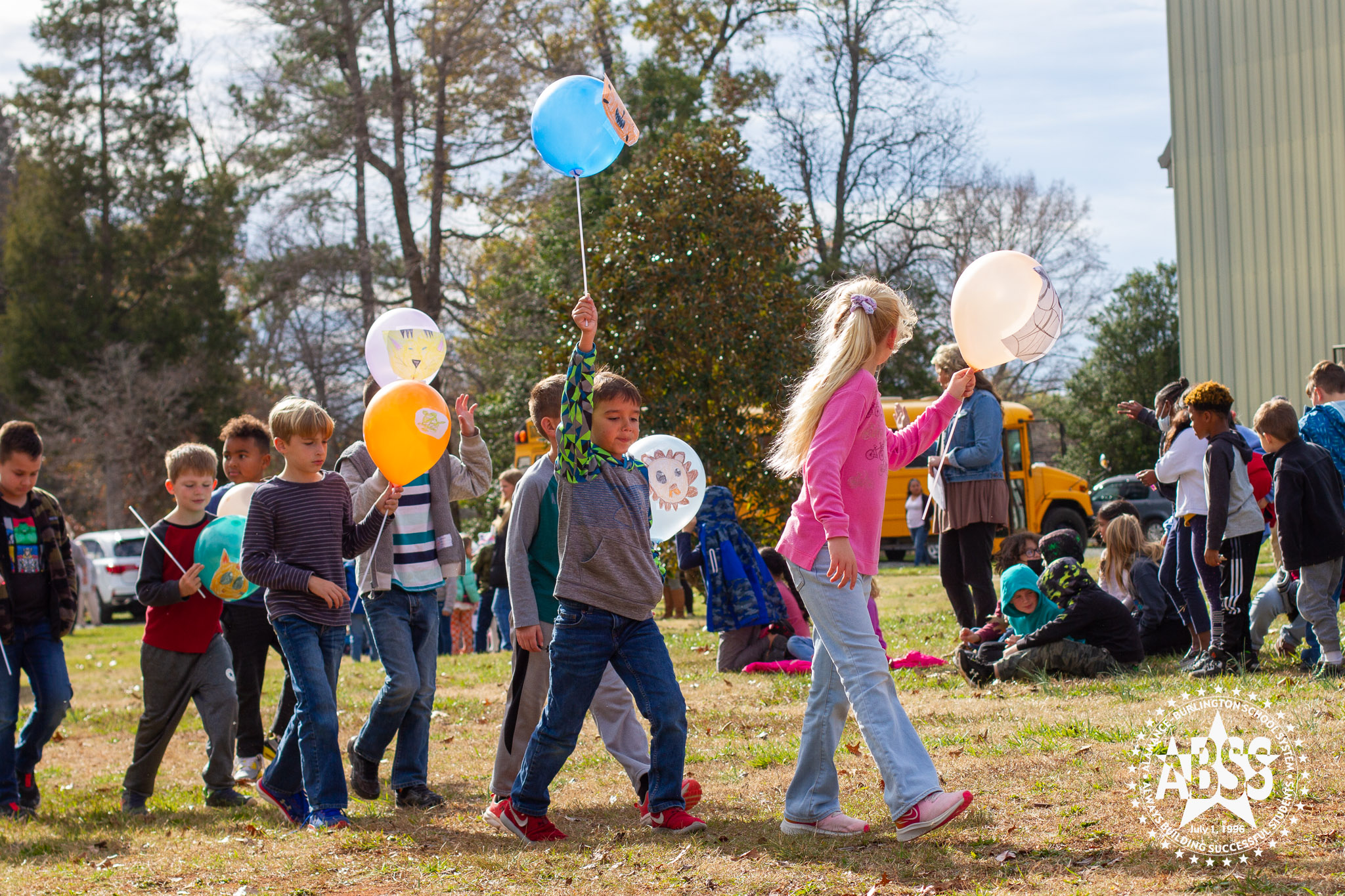 Students from Alexander Wilson Elementary march in a line carrying balloon floats they made during the Balloons Over AWE event for Thanksgiving