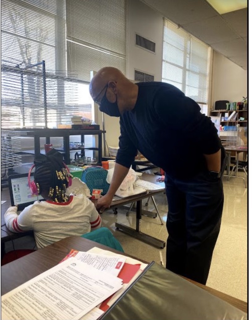 School Social Worker Terry Scott leans over a student working at a table