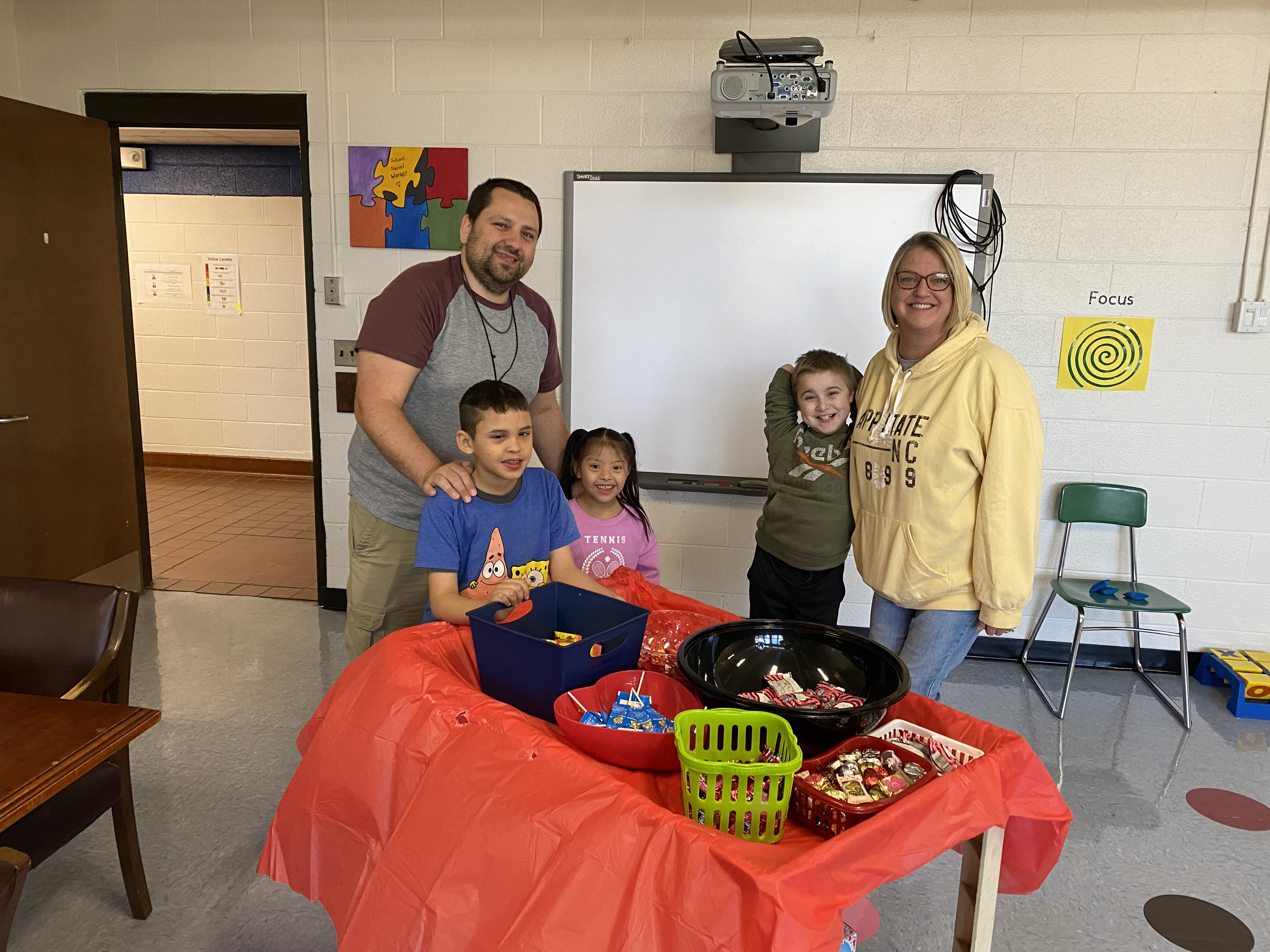 Two school stand with elementary students at South Graham Elementary with prizes on a table in front of them