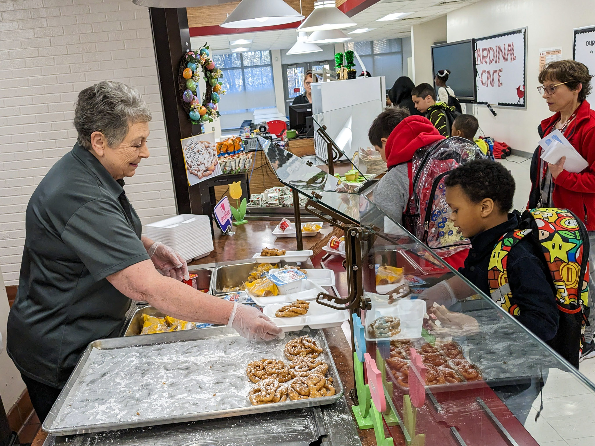 A nutrition specialist serves students breakfast in a school cafeteria
