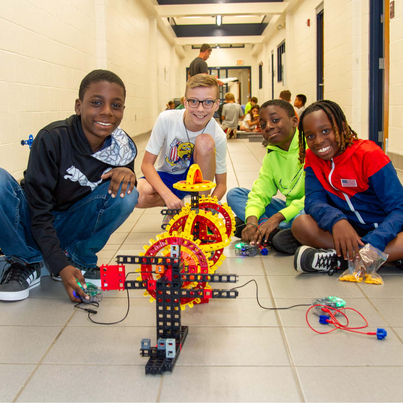 Four boys pose with a contraption they made using blocks and a circuit