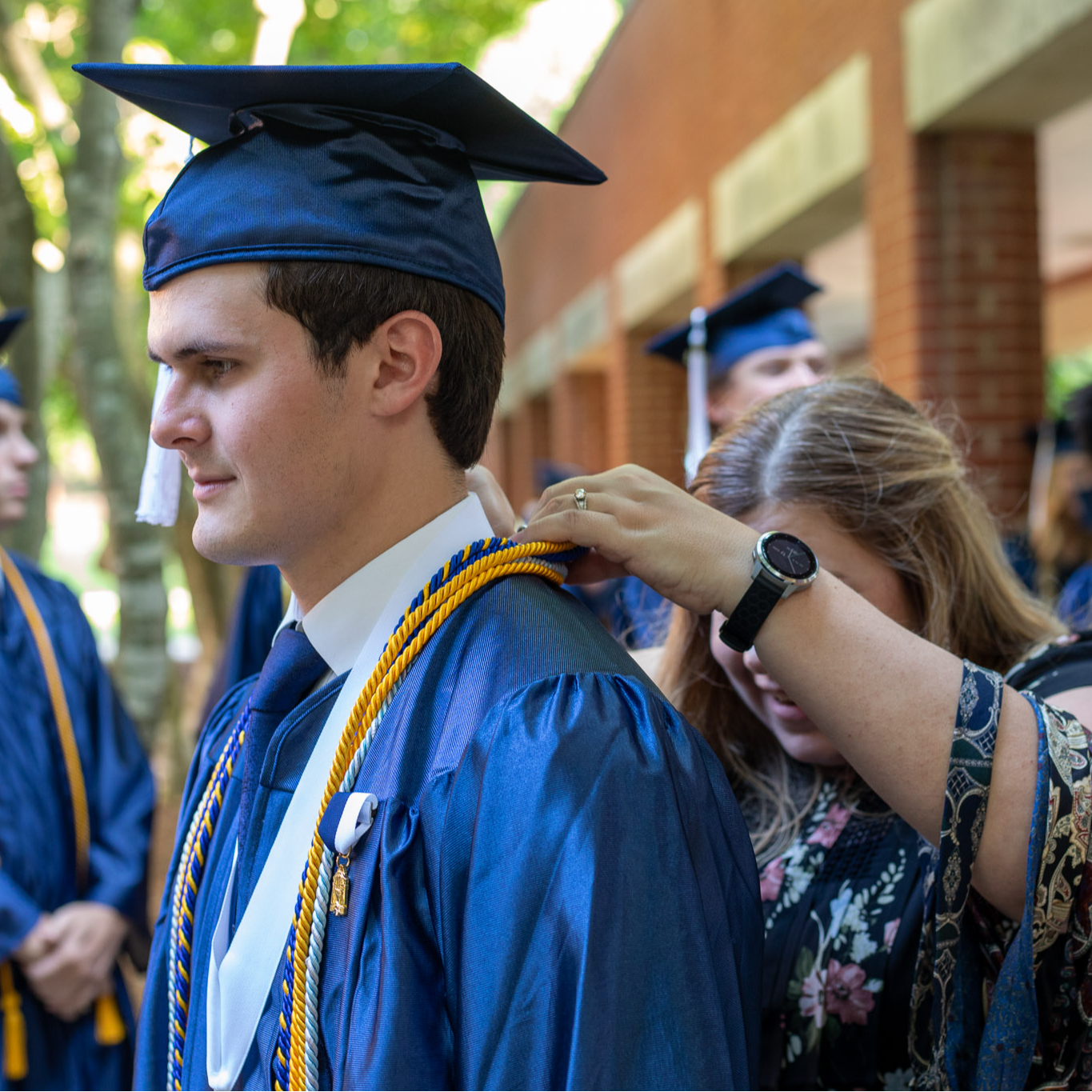 A student at Western Alamance High School has his cap and gown adjusted