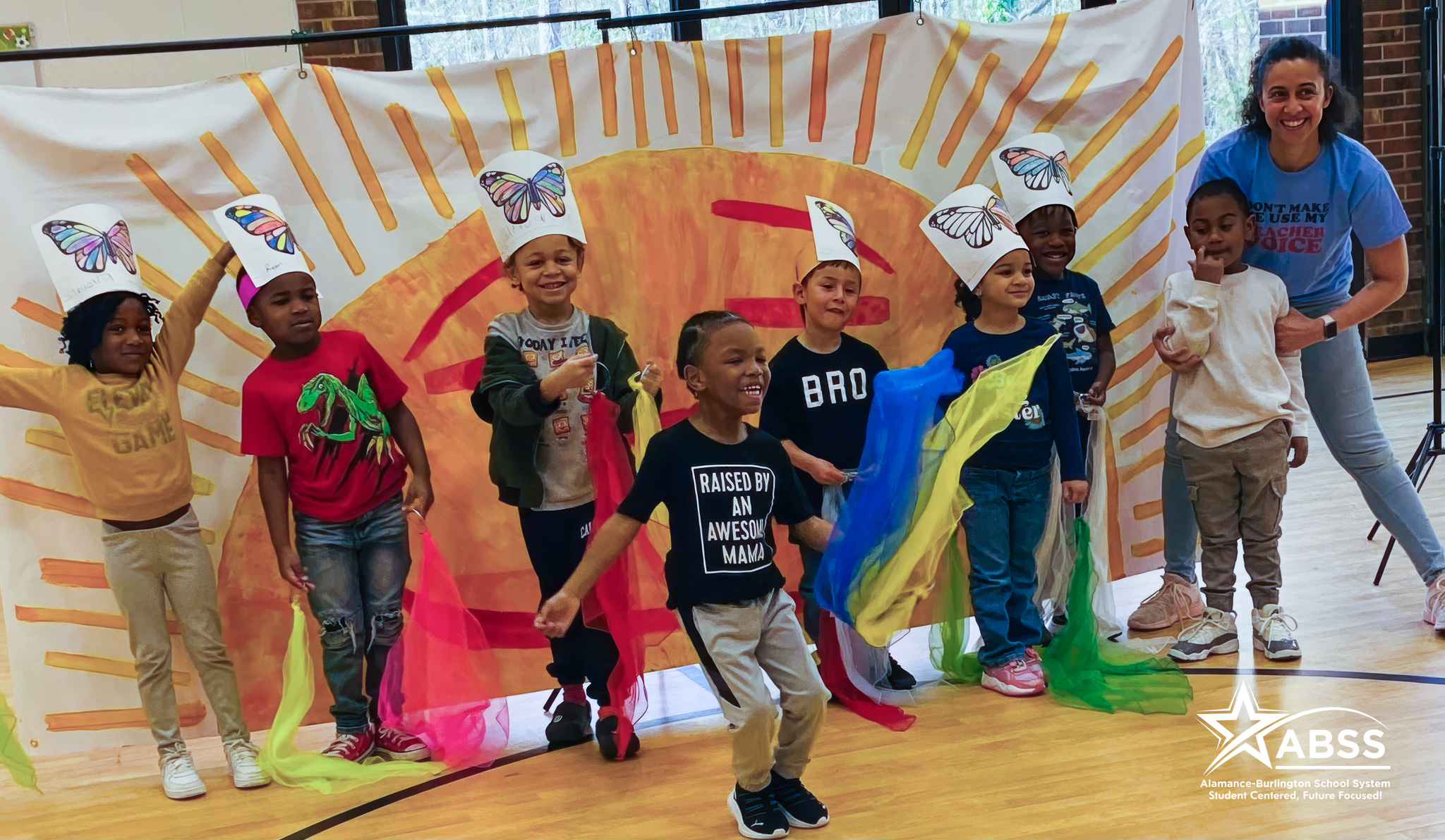 Pre-Kindergarten students standing in front of a larger painted sun during a school play