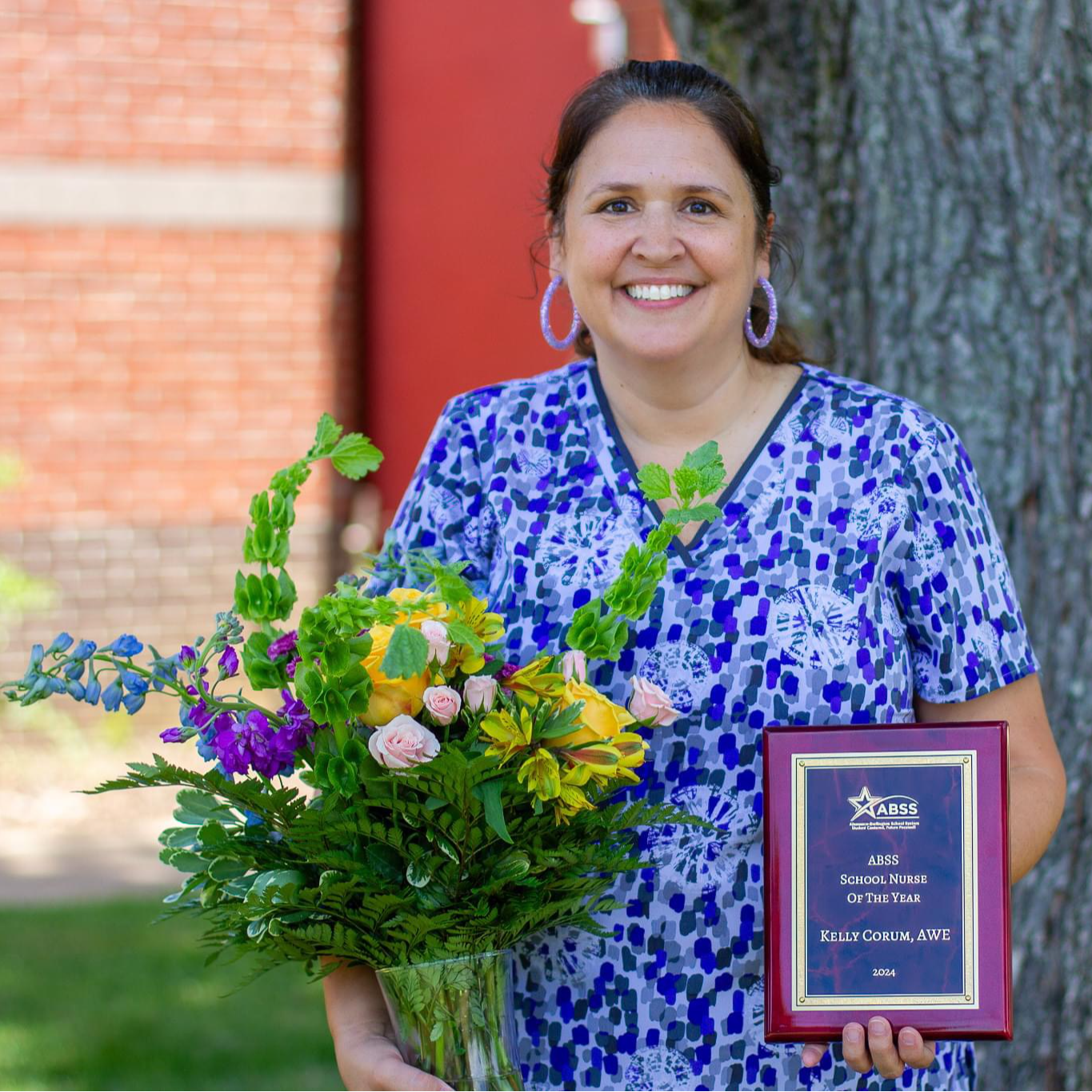 Kelly Corum, School Nurse of the Year, standing outside with flowers