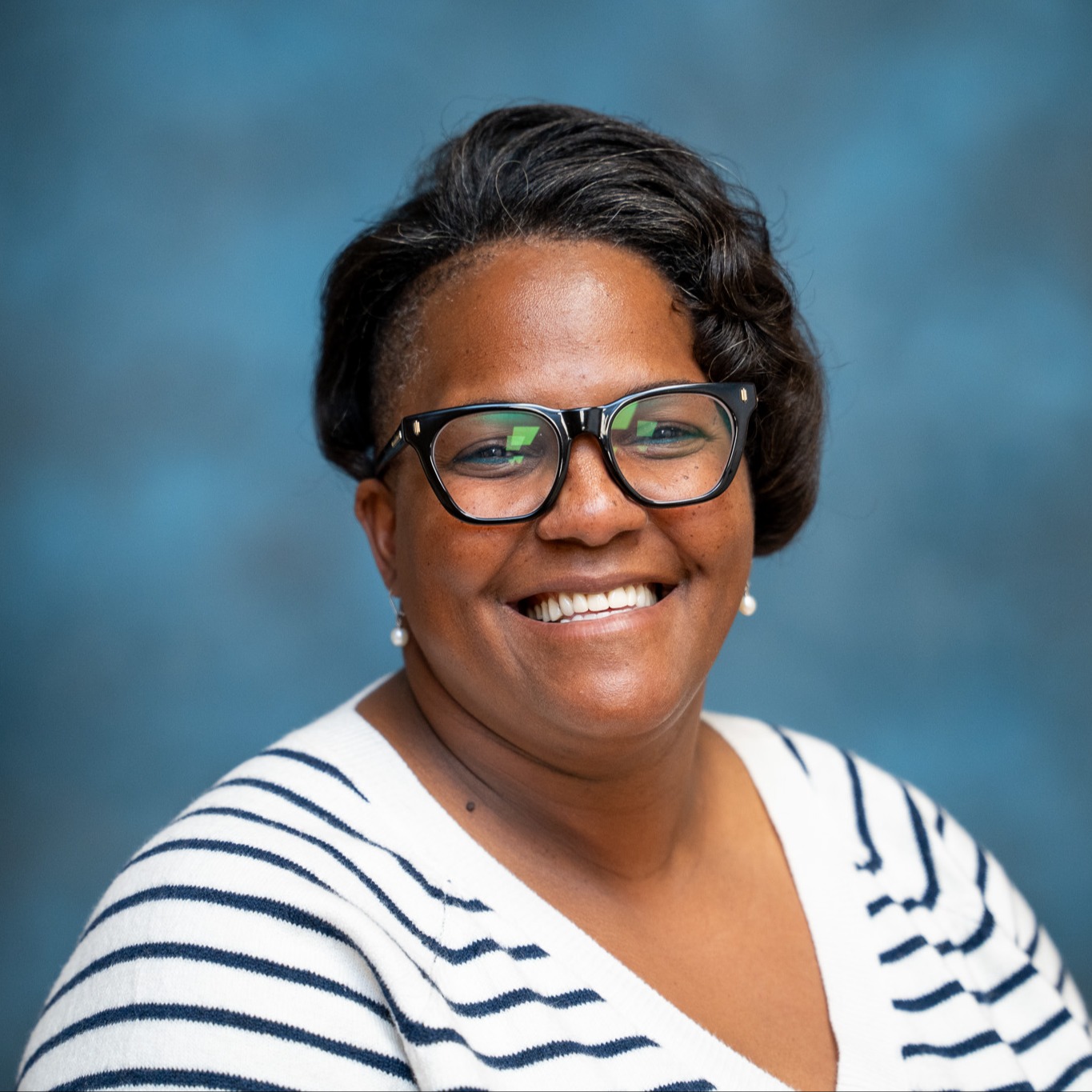 Portrait of ABSS Board Member Tameka Harvey wearing a white striped top