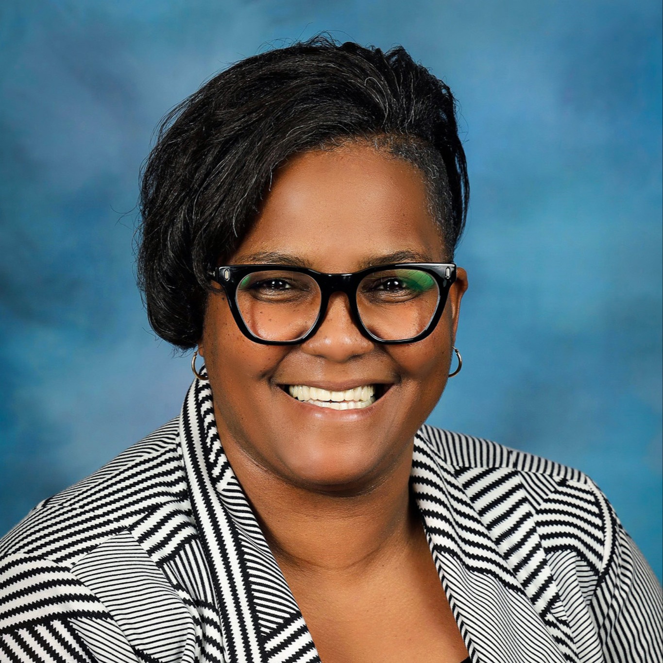 Portrait of ABSS Board Member Tameka Harvey wearing a white striped top
