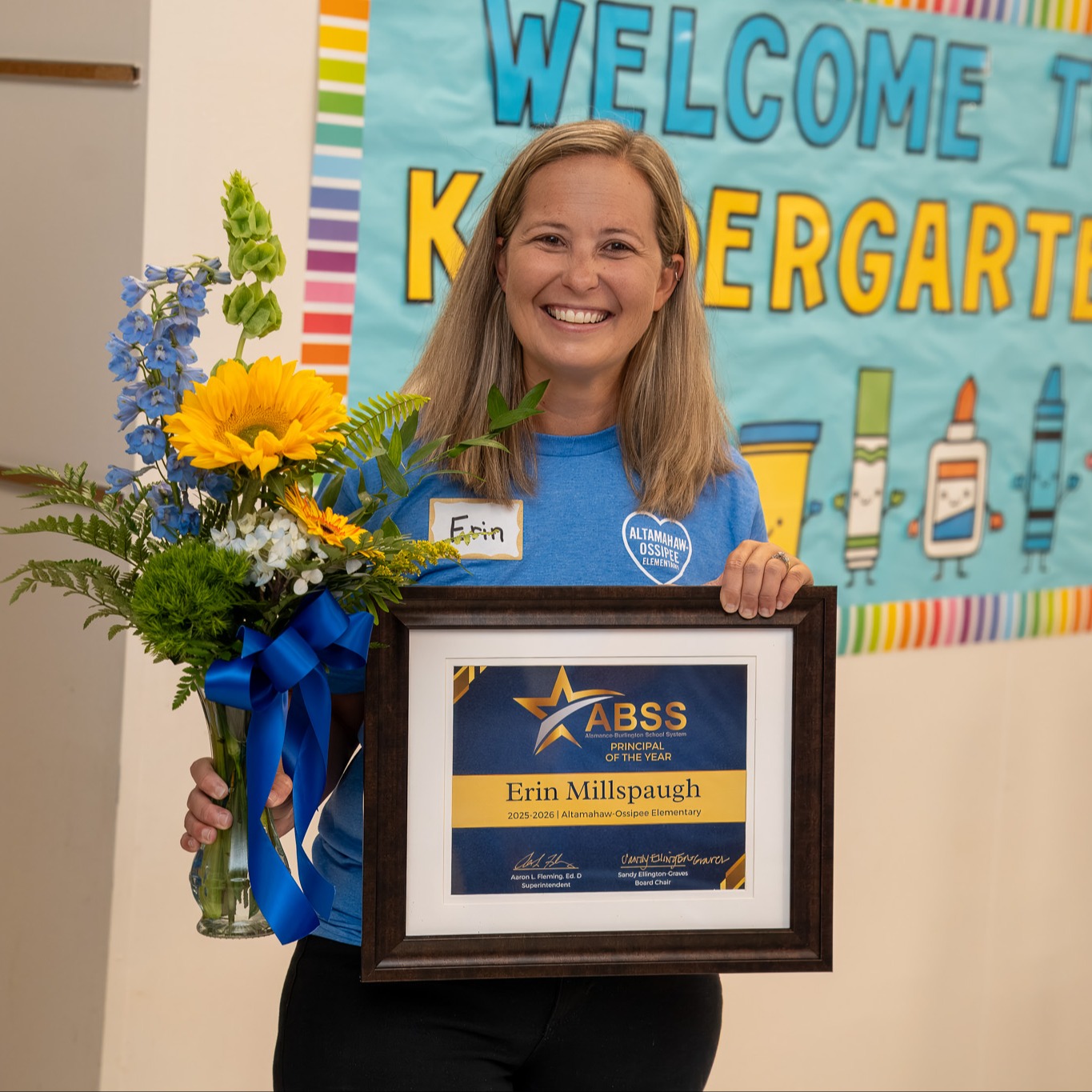 Erin Millpaugh, Principal of Altamahaw-Ossipee Elementary, holding flowers and a Principal of the Year award