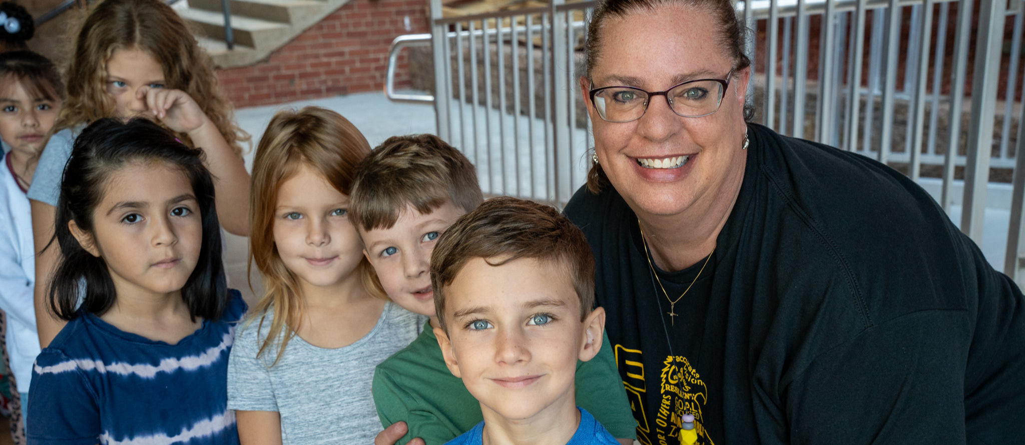An elementary teacher stands beside her class outside of the school