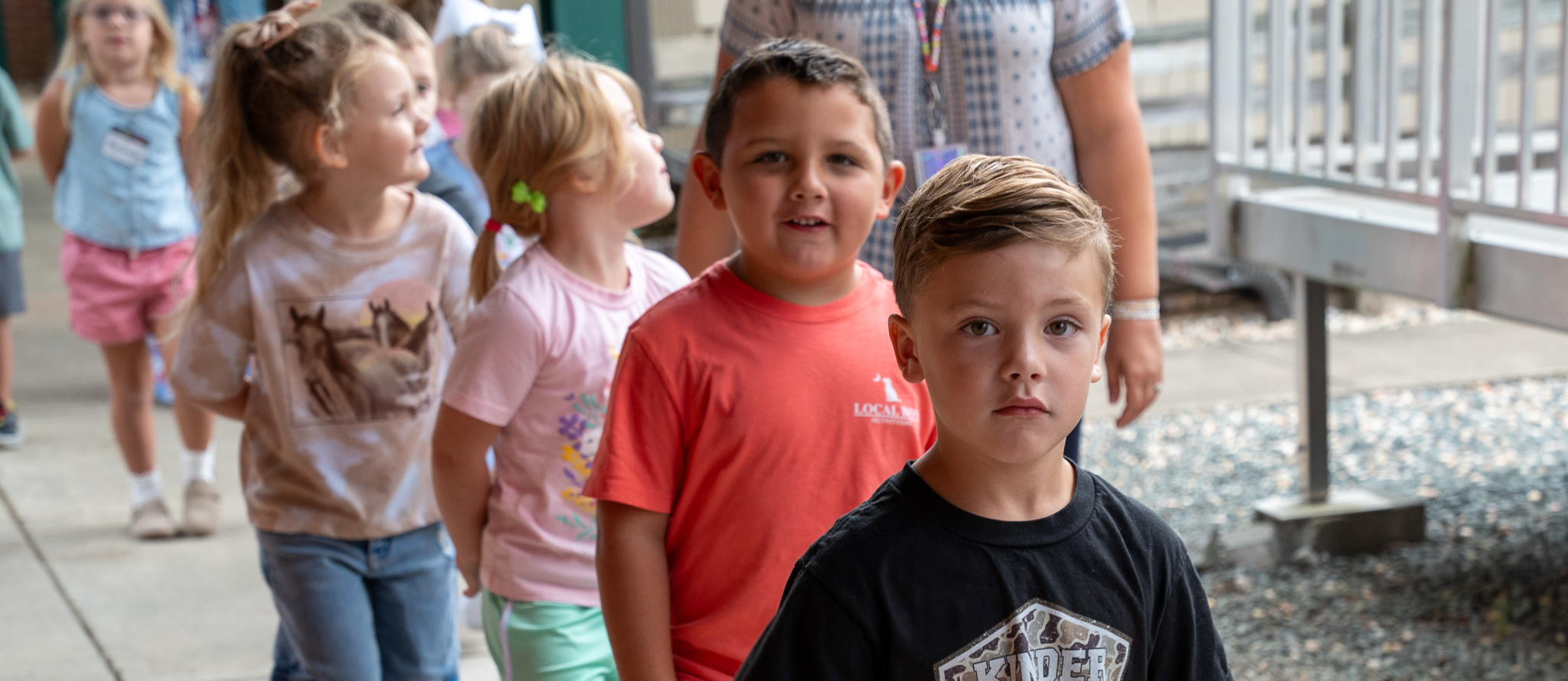 A line of kindergarten students, mostly boys, walking outside in an orderly fashion