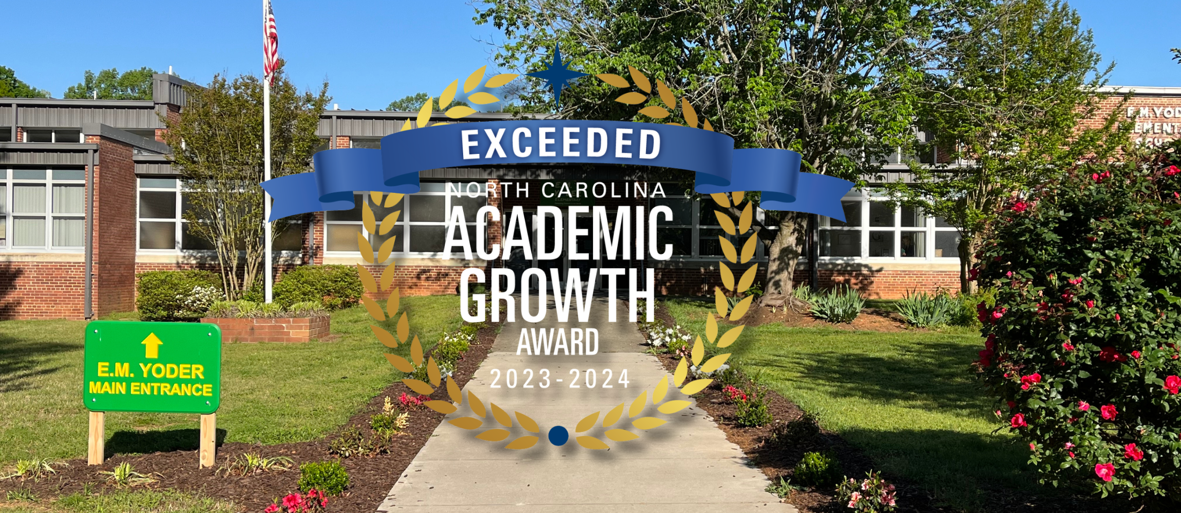 E.M. Yoder Elementary School main entrance showing a walkway to the front door, over top of the photograph is a medal showing that EM Yoder exceeded grown for the 2023-2024 school year