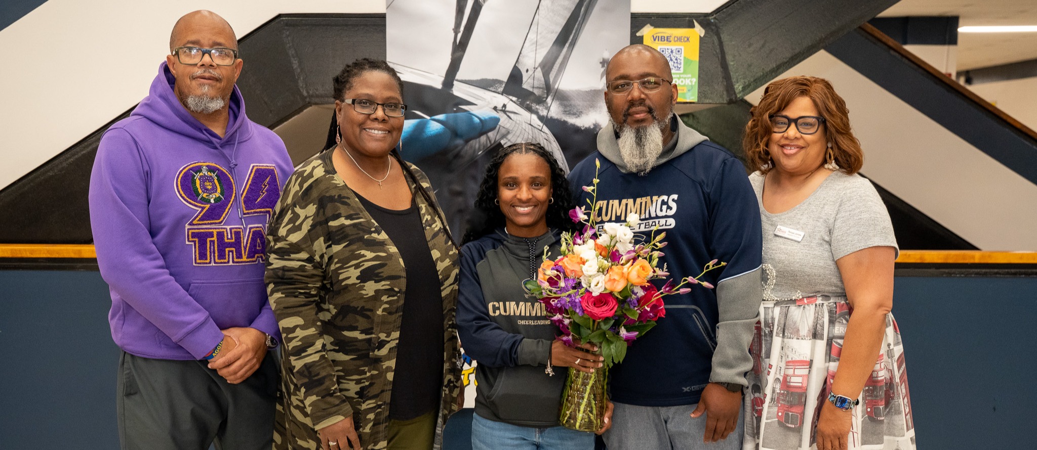 Exceptional Children Educator of Excellence Jasmine Plummer stands next to school administrators in the lobby at Cummings