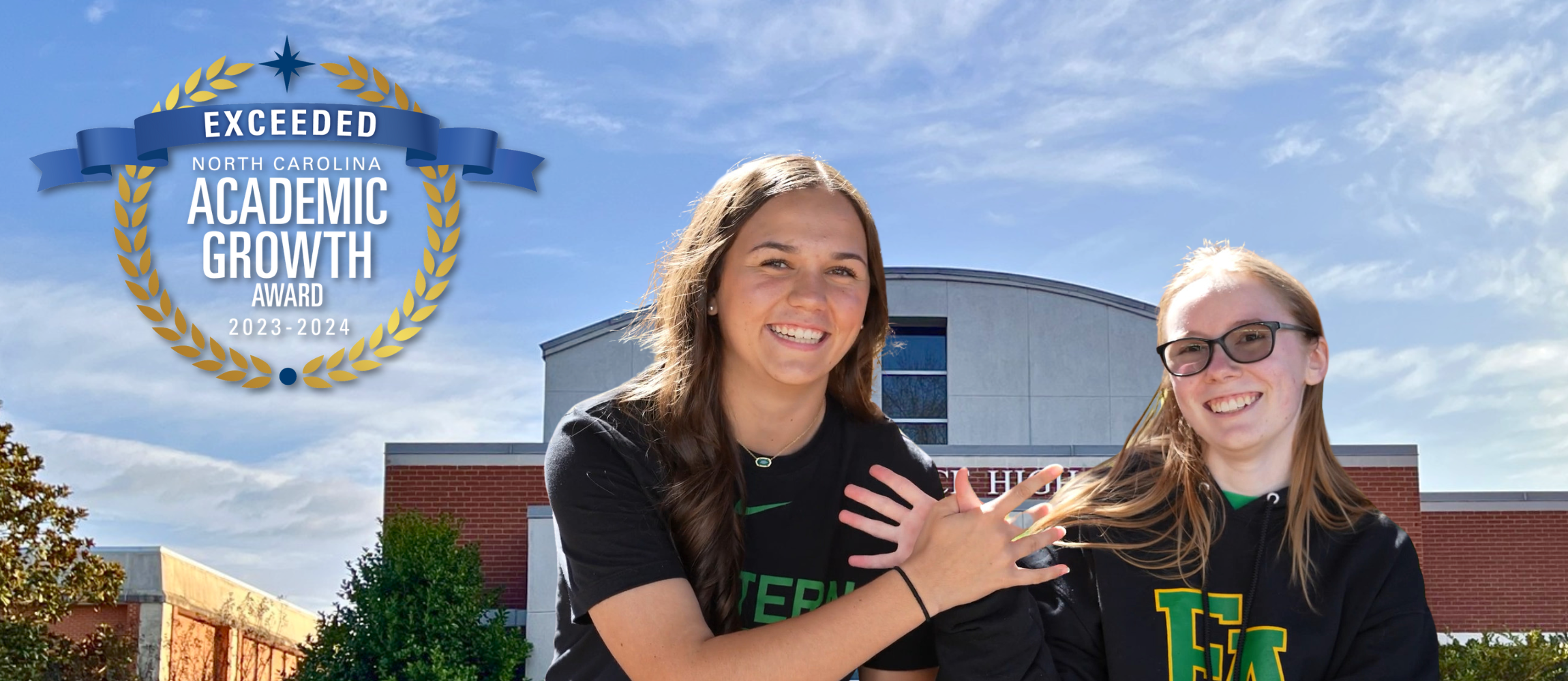 Front of Eastern Alamance High School with a blue sky and a medal in the top left corner showing that Eastern exceeded academic growth and two students wearing black t-shirts making a bird with their hands together