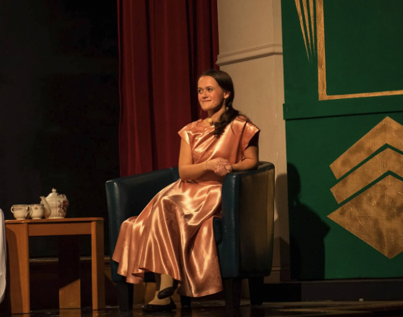 Girl sits on stage in dress