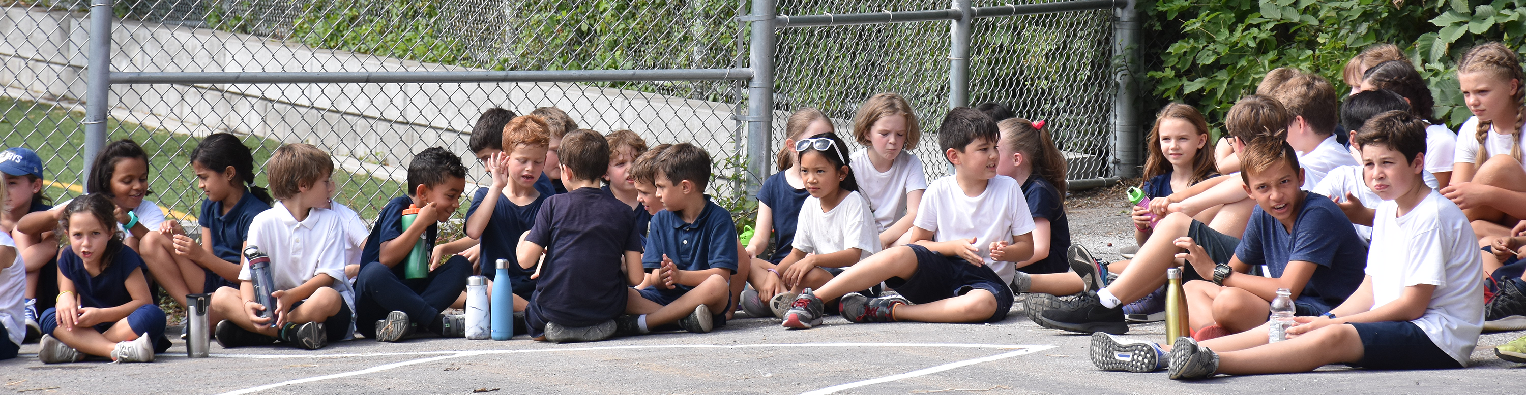 Blessed Sacrament students in uniform sitting in the new playground courtyard.