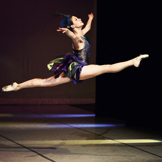 A student dancing on stage in a black dress.
