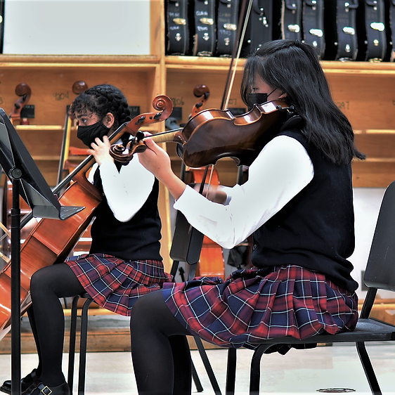 A group of students in uniform practicing string instruments in a classroom.