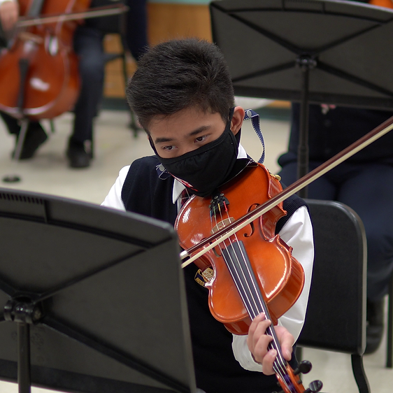 A male student playing a violin. 