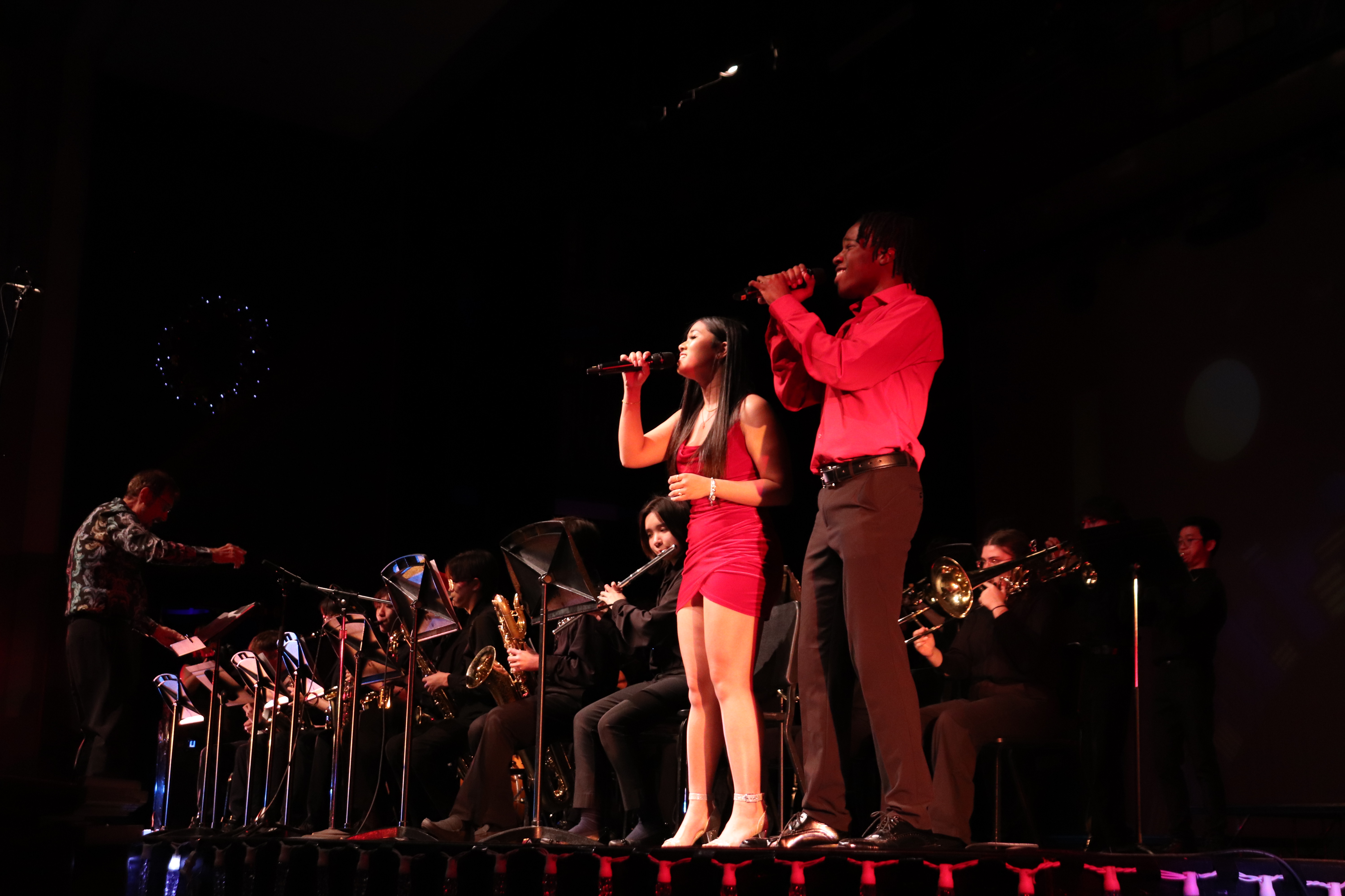 two people singing on stage with a band