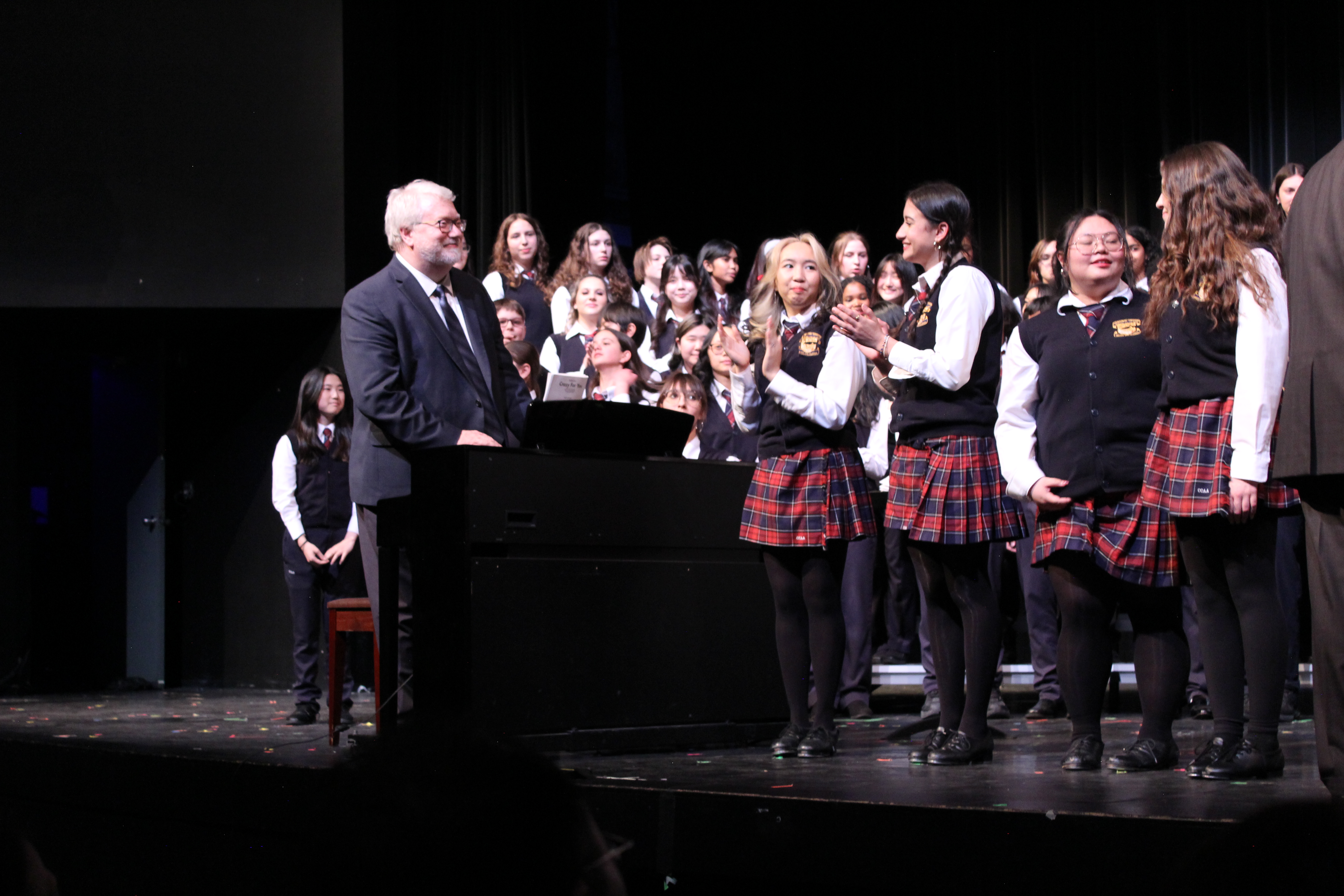 Students and a teacher on stage.