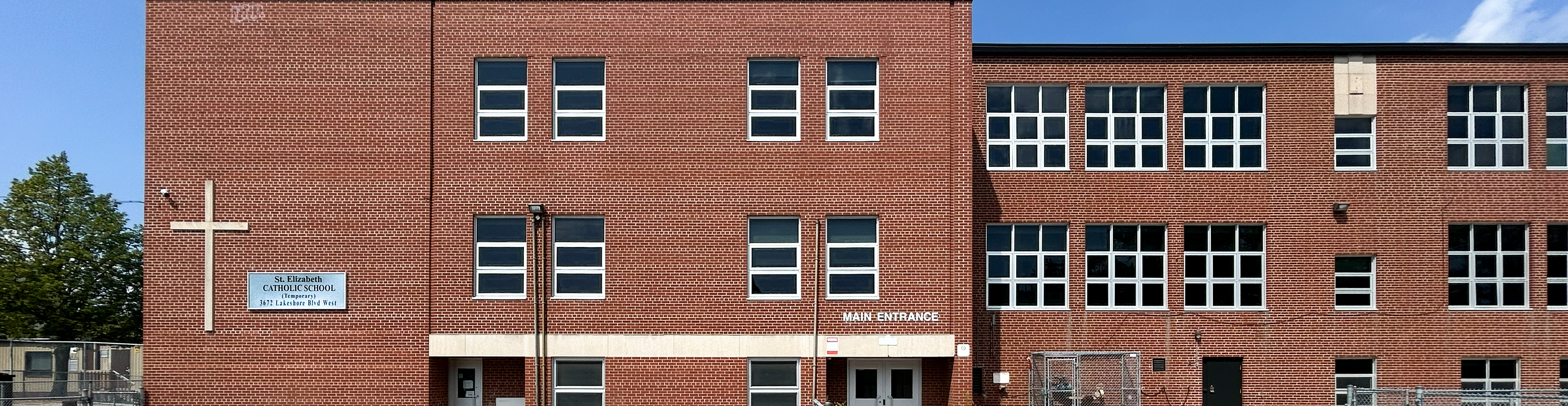 Photo of the St. Elizabeth school building, showing a red brick building with a giant cross and the school name on the front wall of the building
