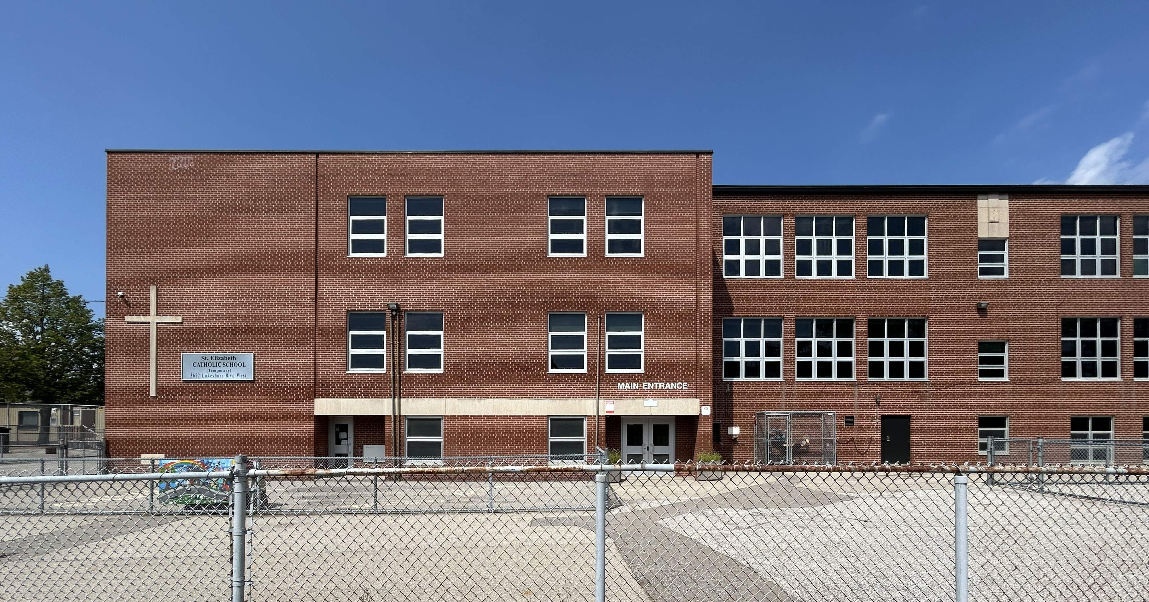 Photo of the St. Elizabeth school building, showing a red brick building with a giant cross and the school name on the front wall of the building
