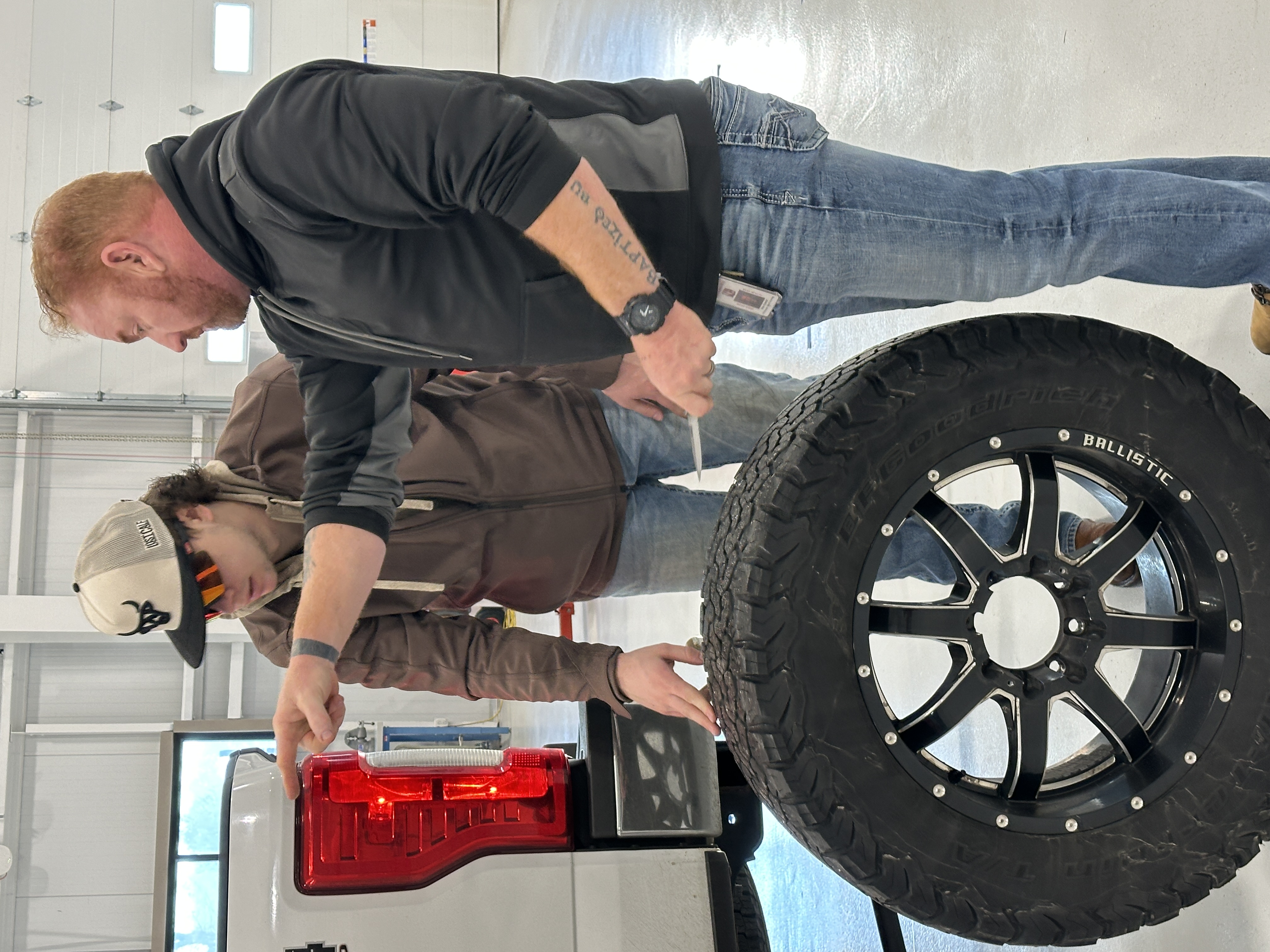 Diesel Instructor showing student  how to properly put tire on truck.