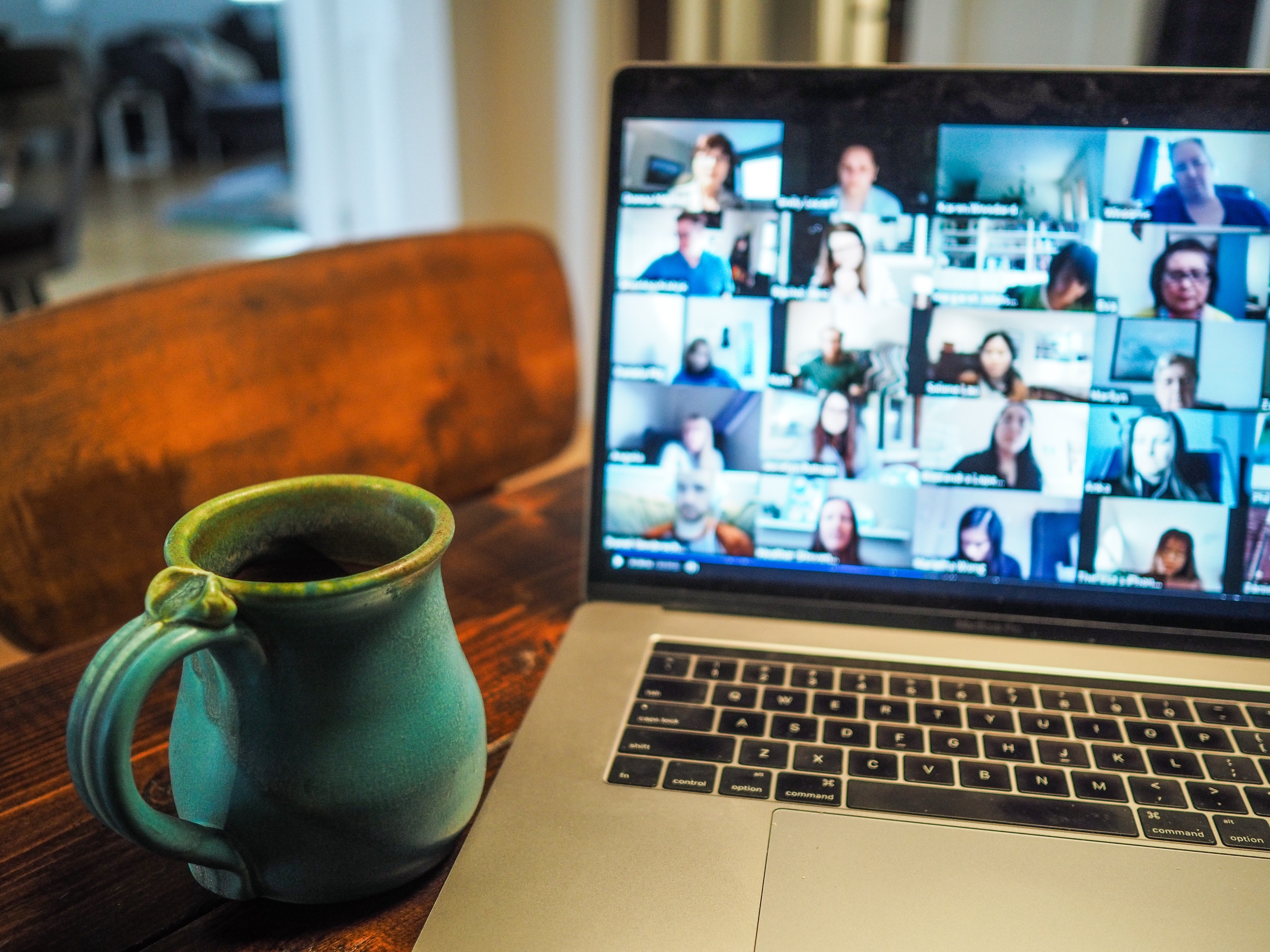 Computer screen with virtual meeting windows and coffee mug.