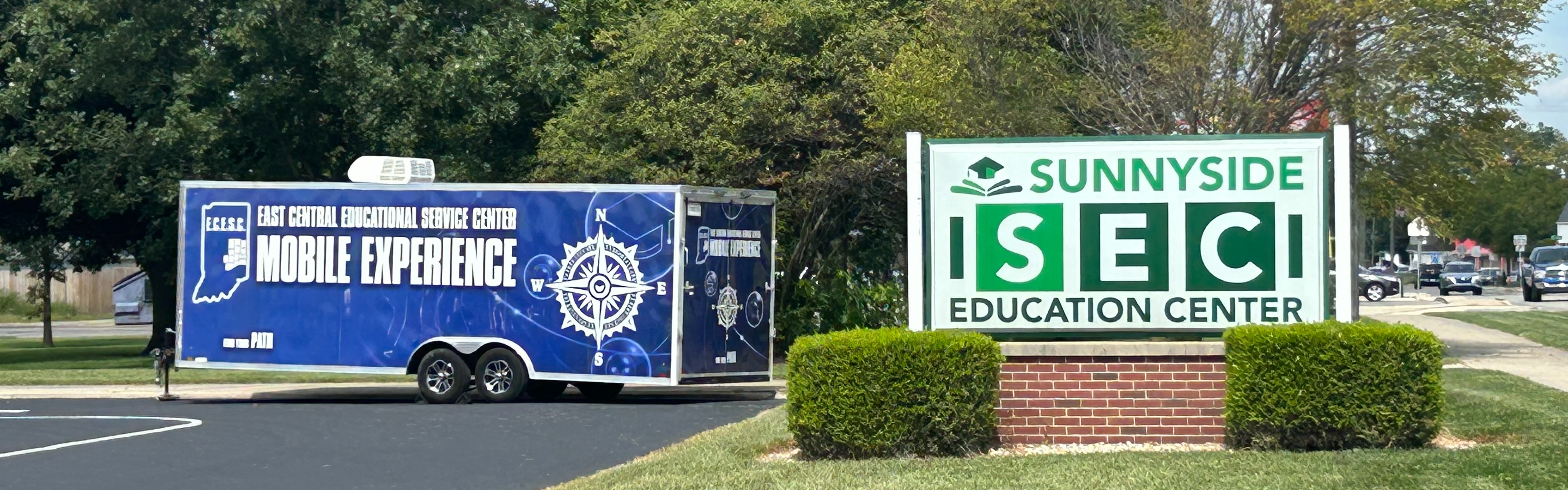 Sign in Front of Building with mobile experience trailer