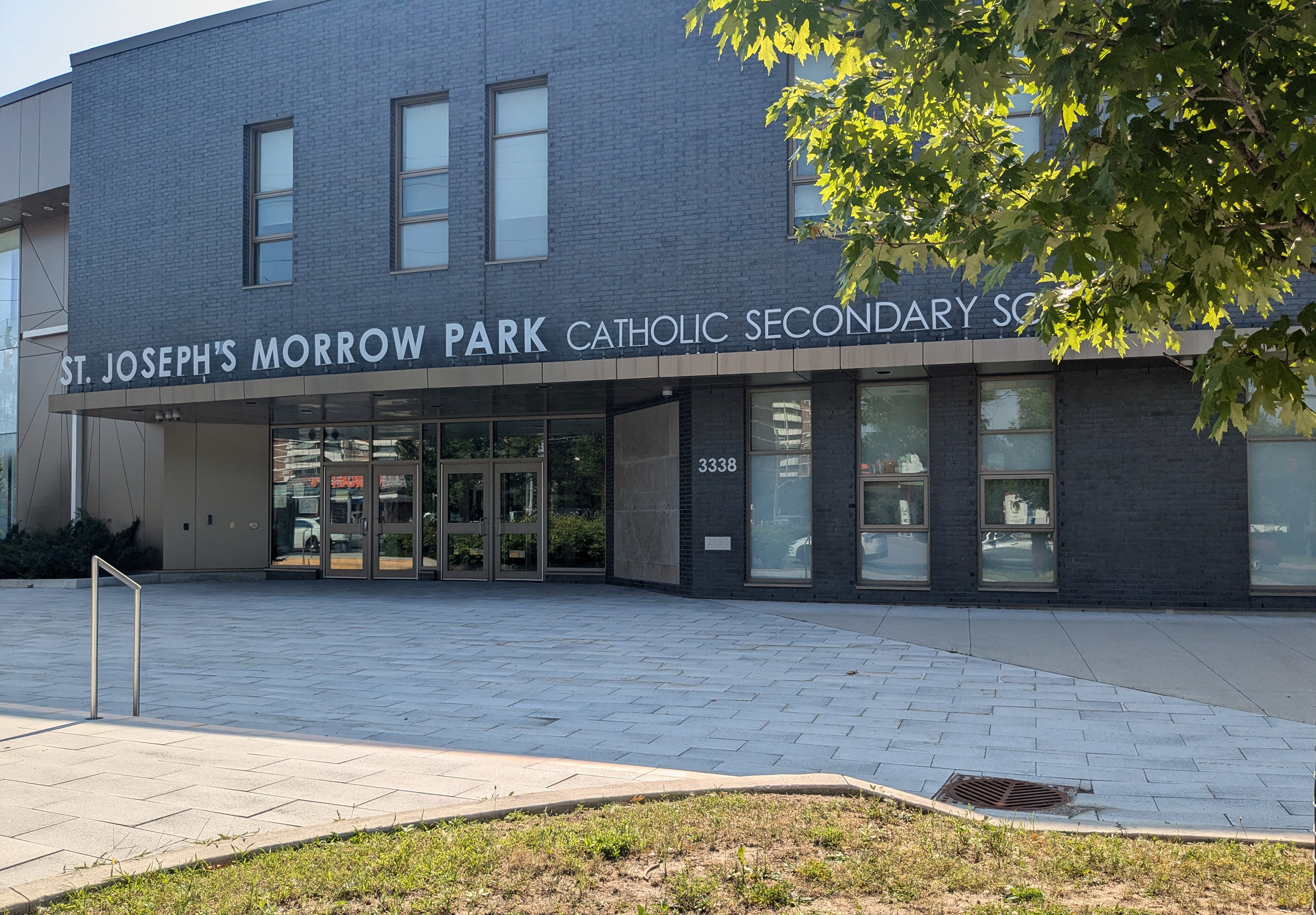 Photo of the St. Joseph's Morrow Park school building, showing a dark grey brick building bordered by trees