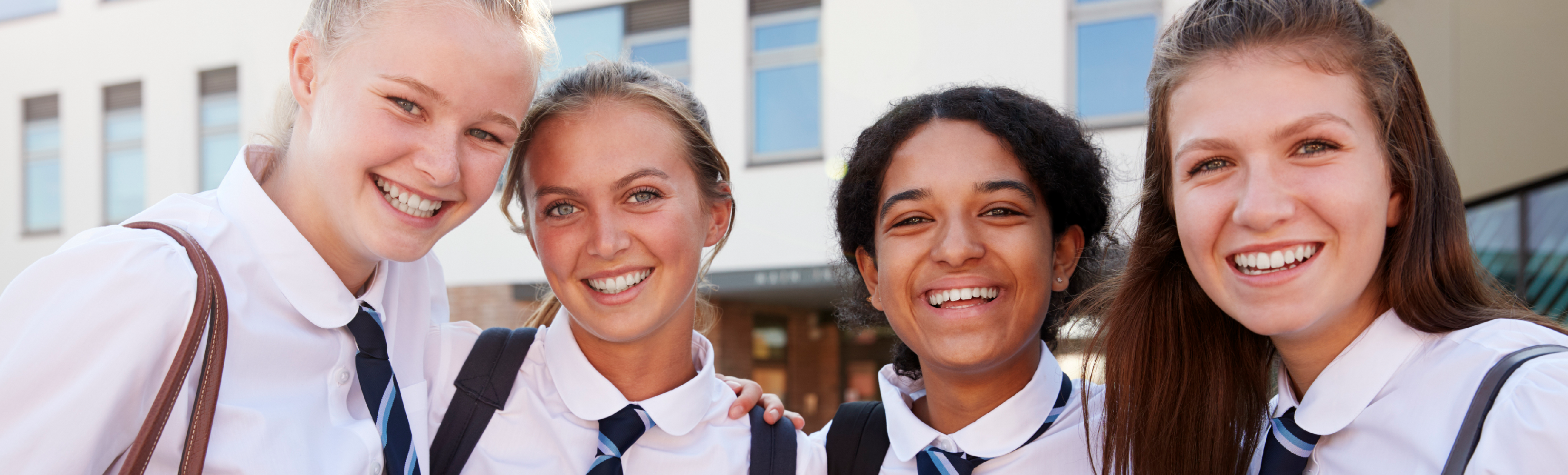 4 female students standing next to each other and smiling at the camera.
